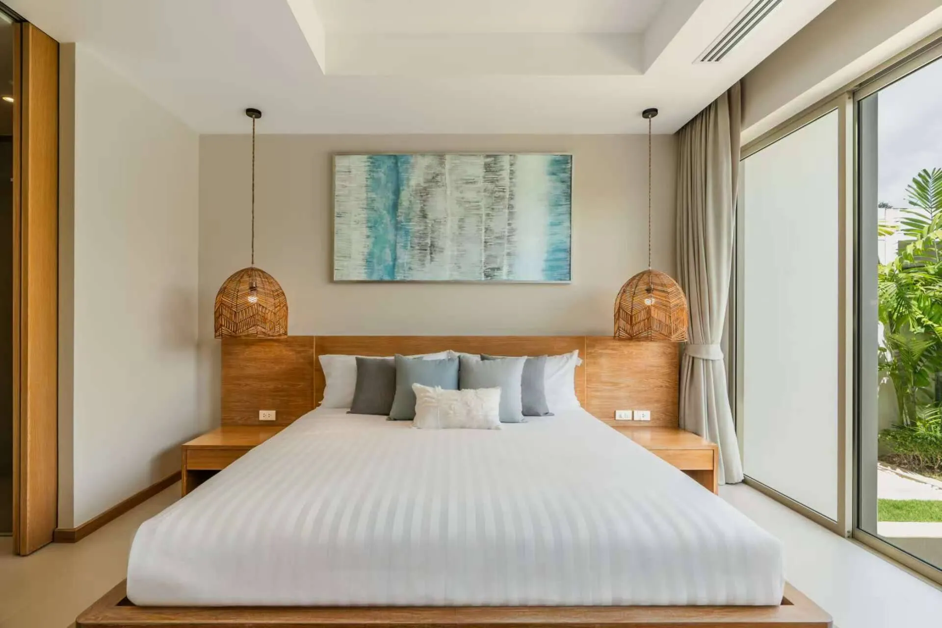 King bed with rattan pendant lights and a blue painting above the headboard