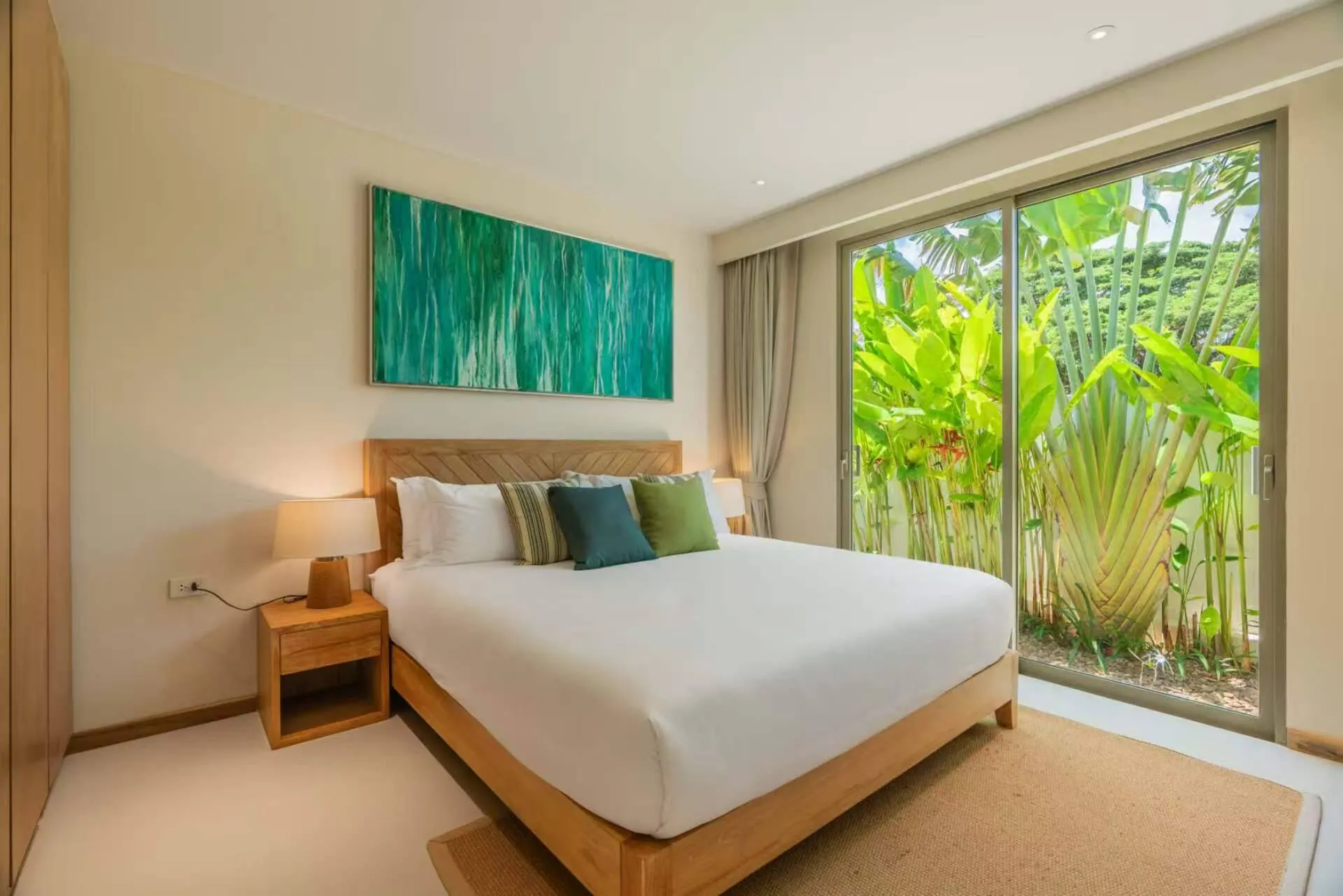 King bedroom with a green abstract painting and a glass door to the garden