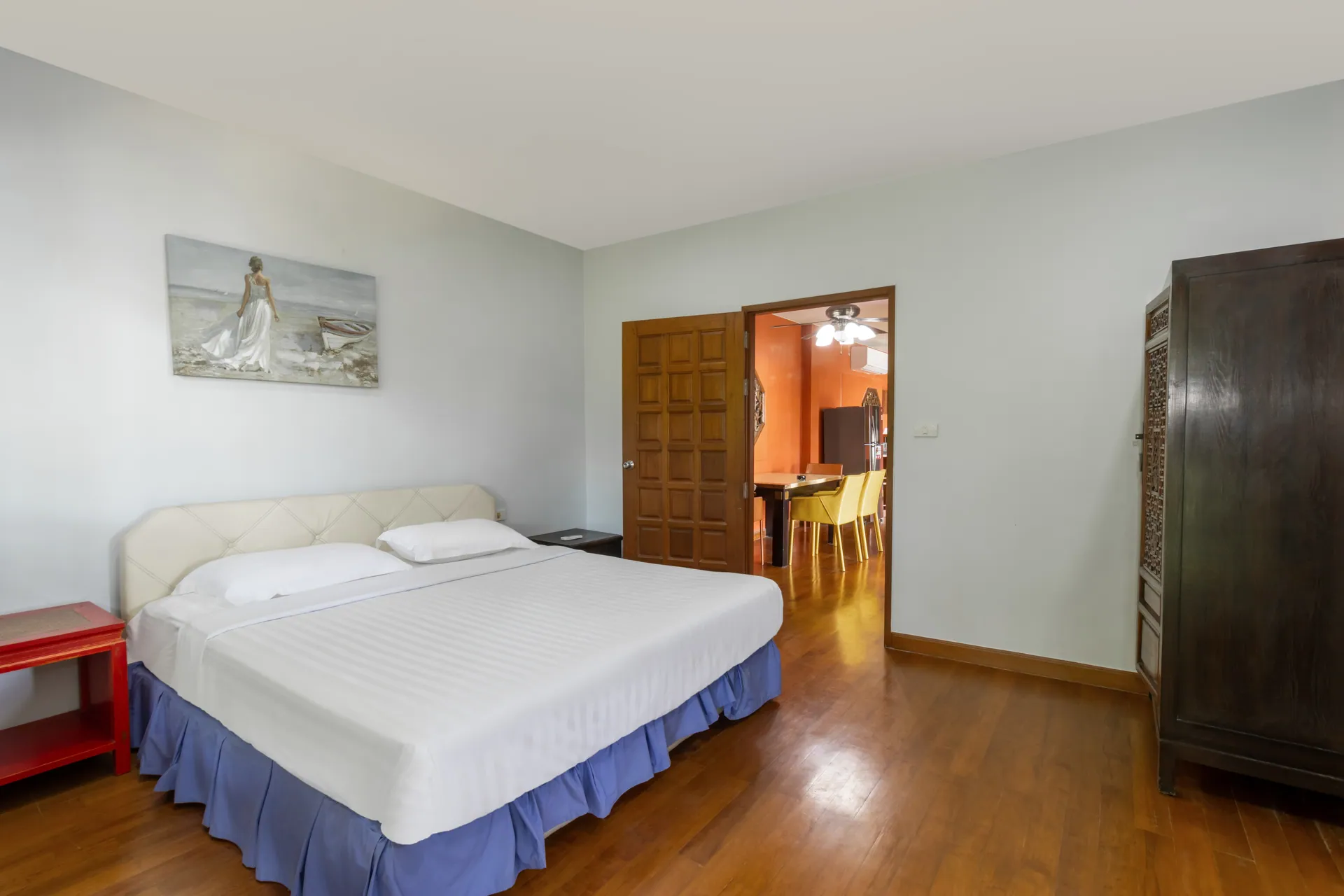 Bedroom with a timber floor, a dark wooden wardrobe and a door to the family lounge