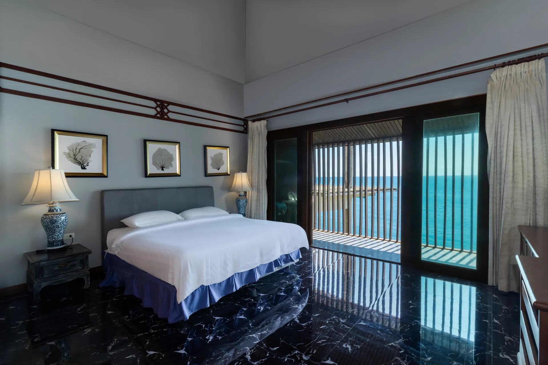 Bedroom with a marble floor and slatted doors framing the sea
