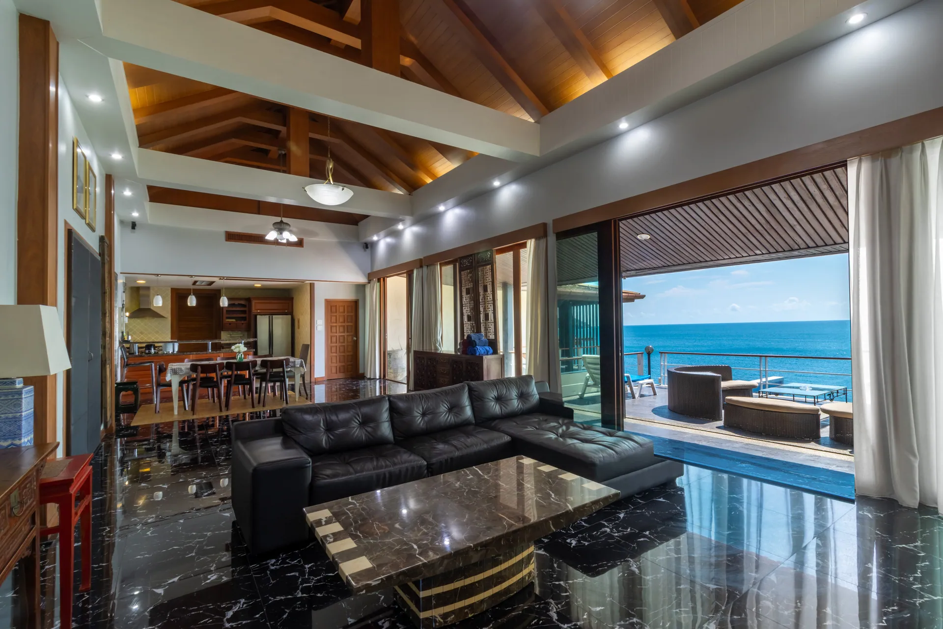 Living room with a timber-vaulted ceiling, leather sofas and sliding doors to the terrace