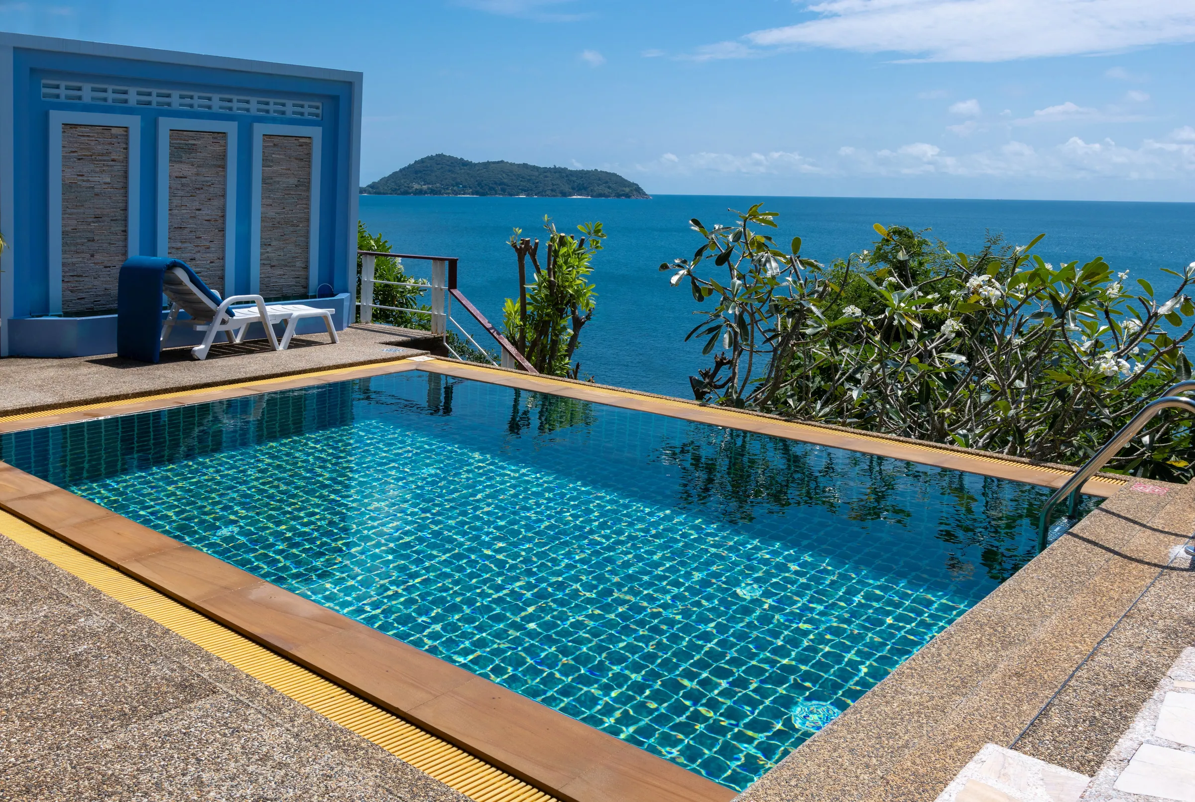 Pool terrace with a sun lounger and a view of an offshore island