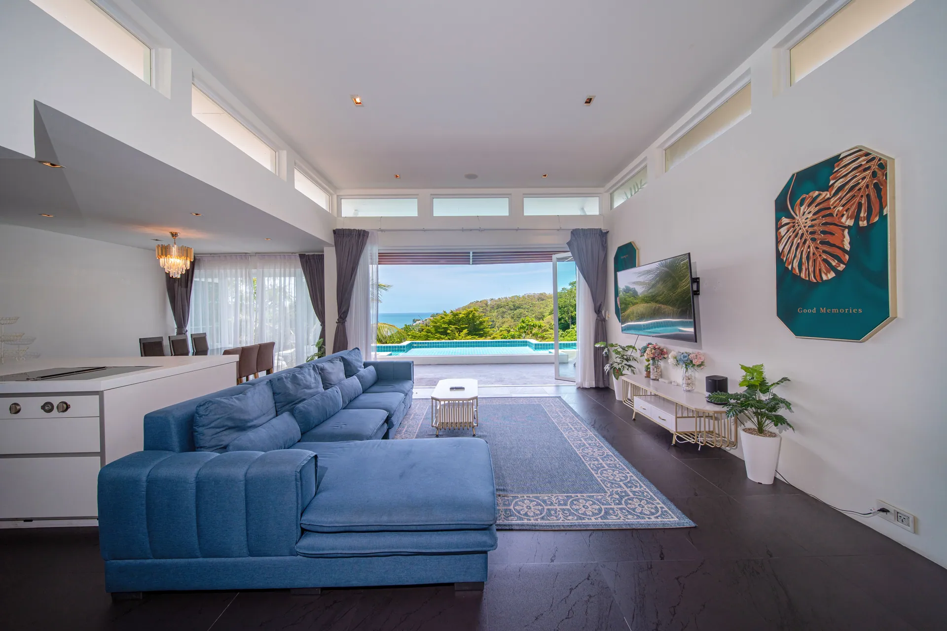 Open-plan living room with a blue sectional sofa and wide doors to the pool and the sea view