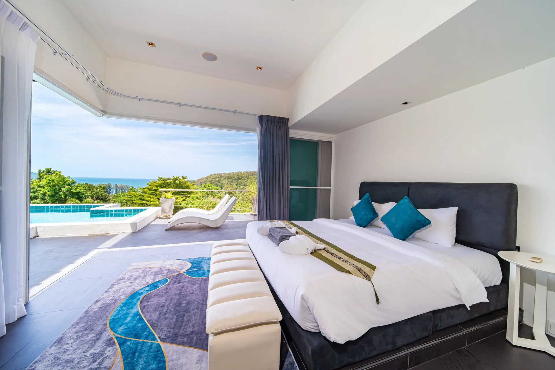 Principal bedroom with glass on two sides, looking across the pool terrace to the sea
