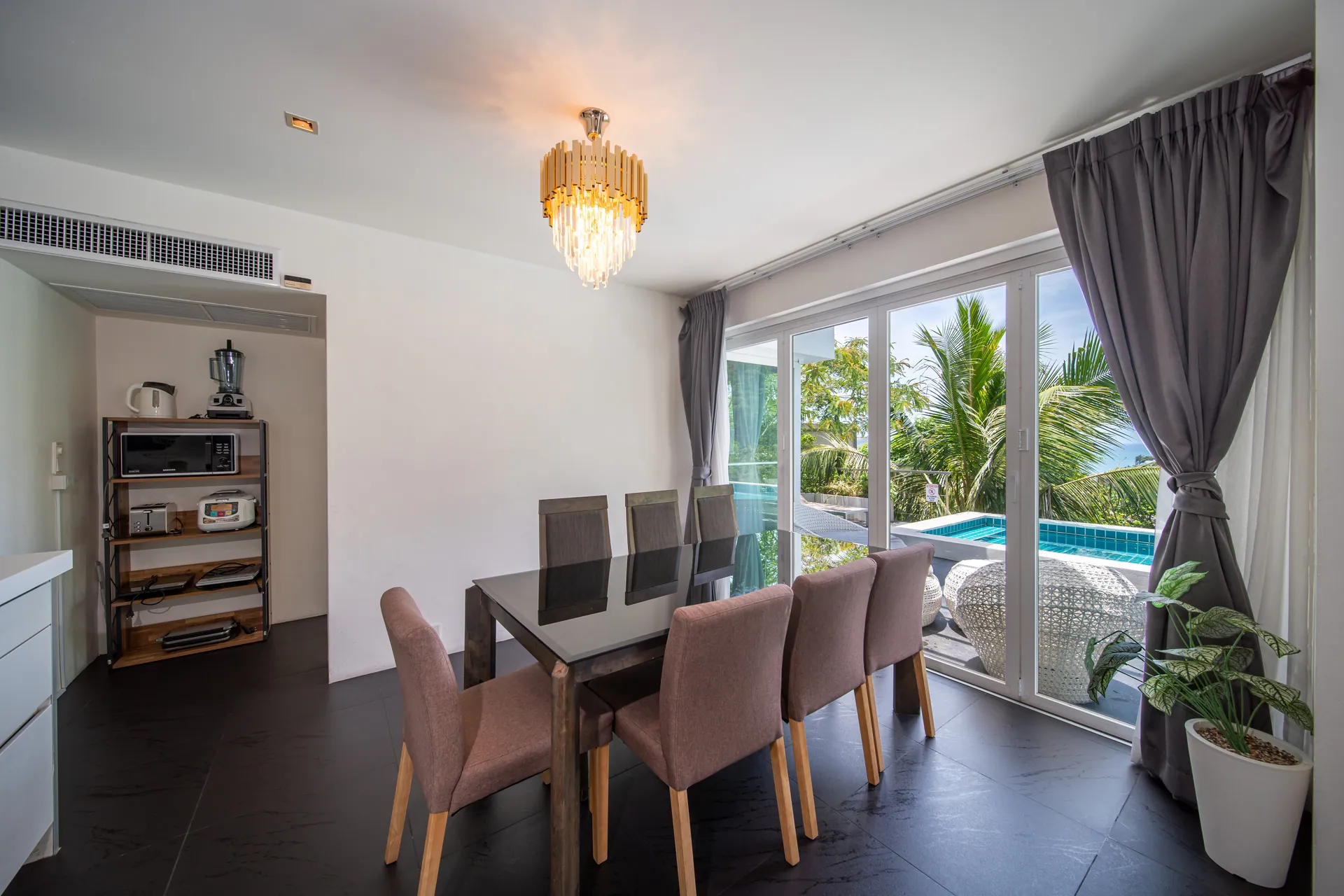 Dining table for a large group beside tall windows looking out to palms and the pool
