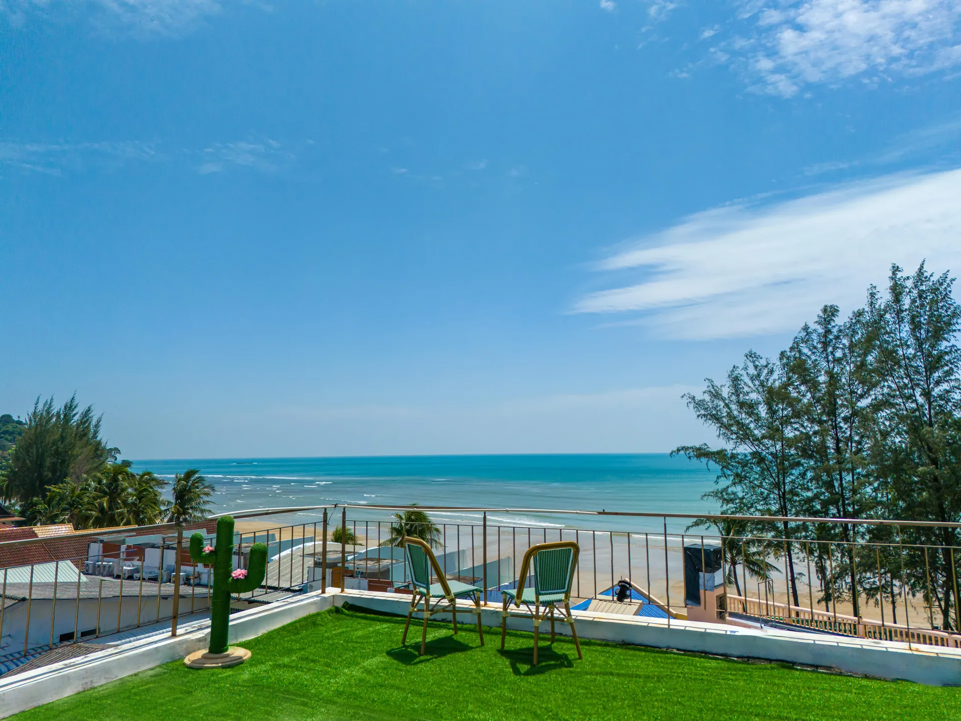 Rooftop lawn terrace with two café chairs, looking over the beach trees to the Andaman Sea