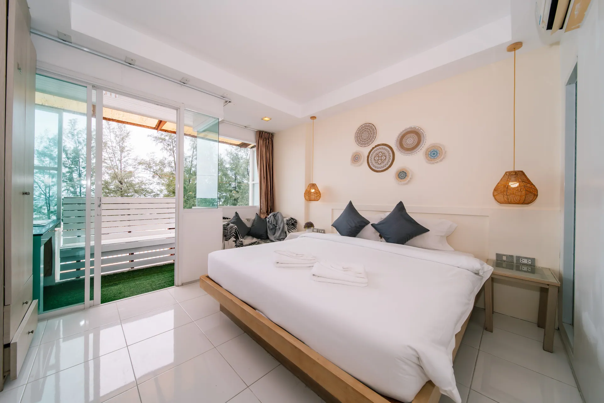 Standard Room with a king bed, rattan pendant lights and a glass door to the balcony