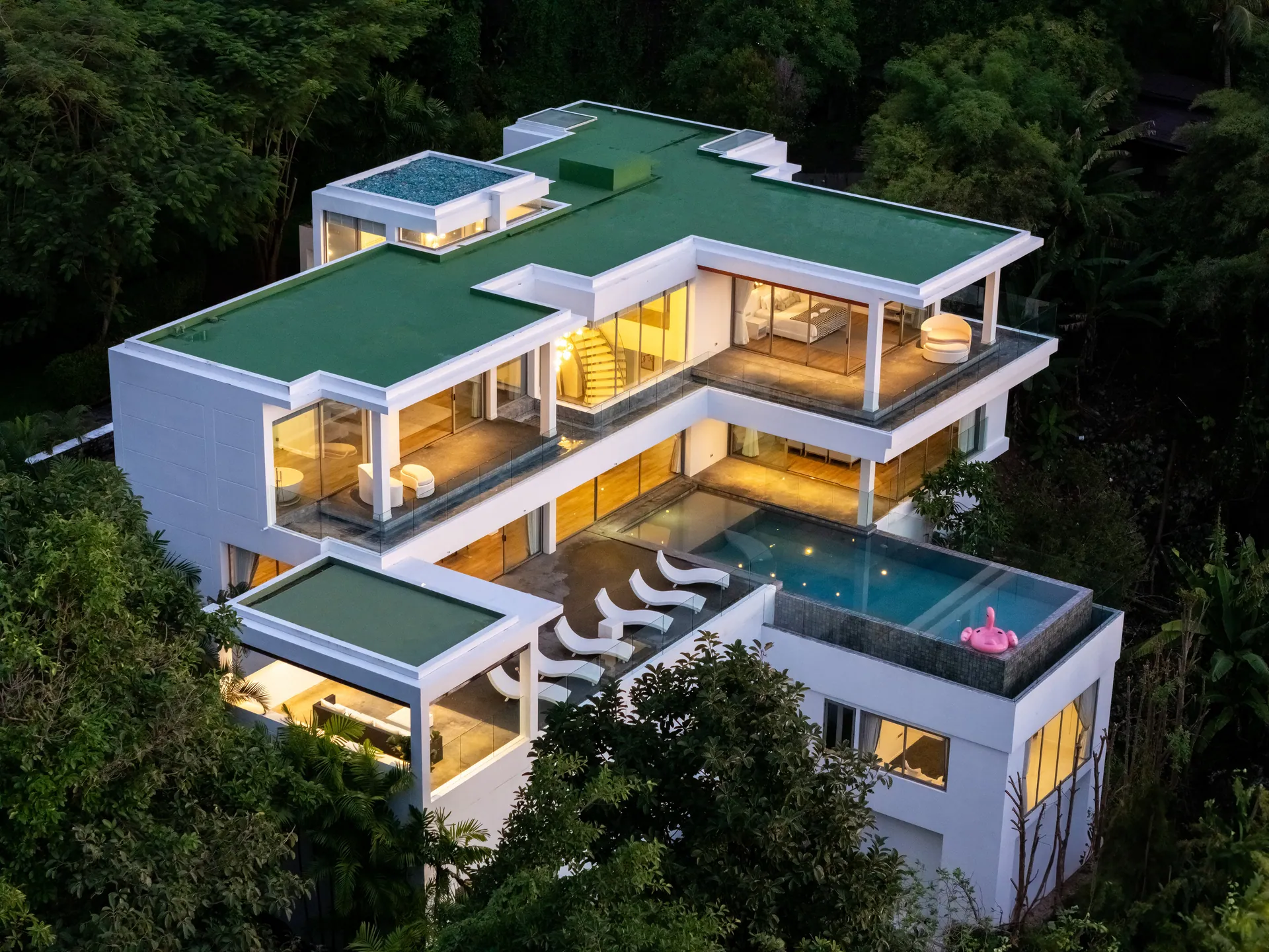 Aerial view of the three-level villa on the wooded hillside at dusk