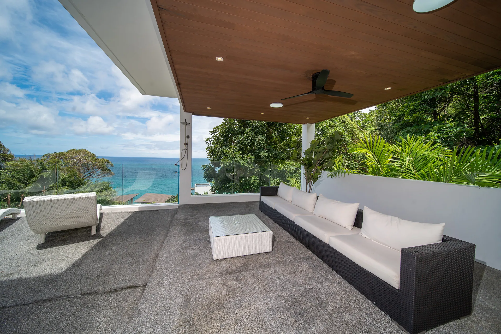 Covered sala with outdoor sofas and a glimpse of the sea