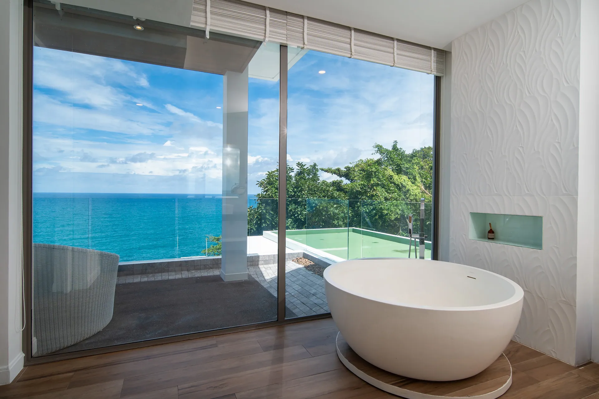 Freestanding bath beside a glass wall facing the sea