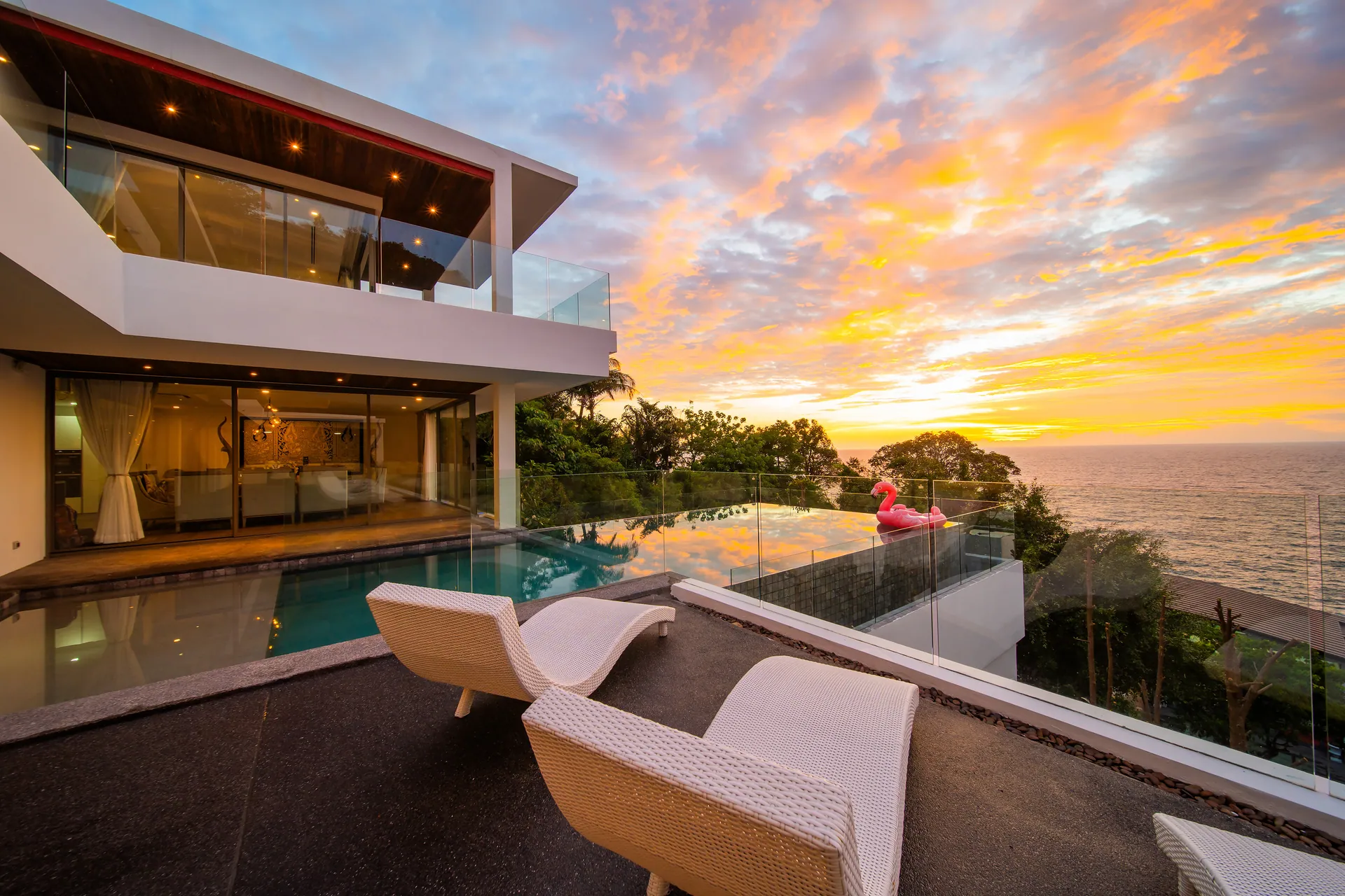 Infinity pool and sun loungers on the terrace at sunset, with the Andaman Sea beyond