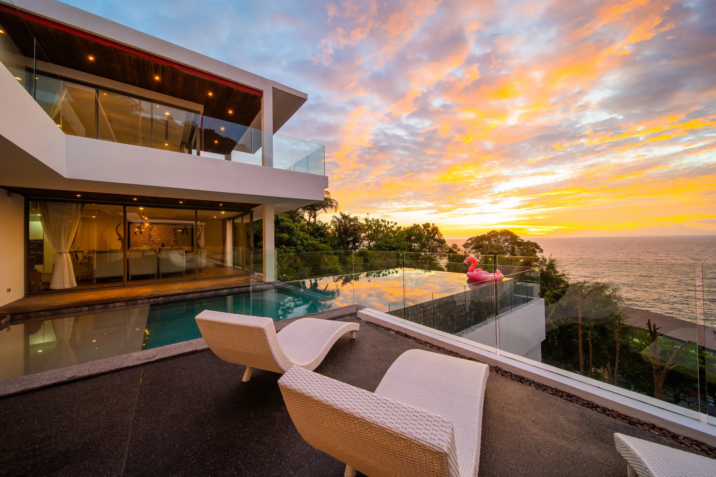 Infinity pool and sun loungers on the terrace at sunset, with the Andaman Sea beyond