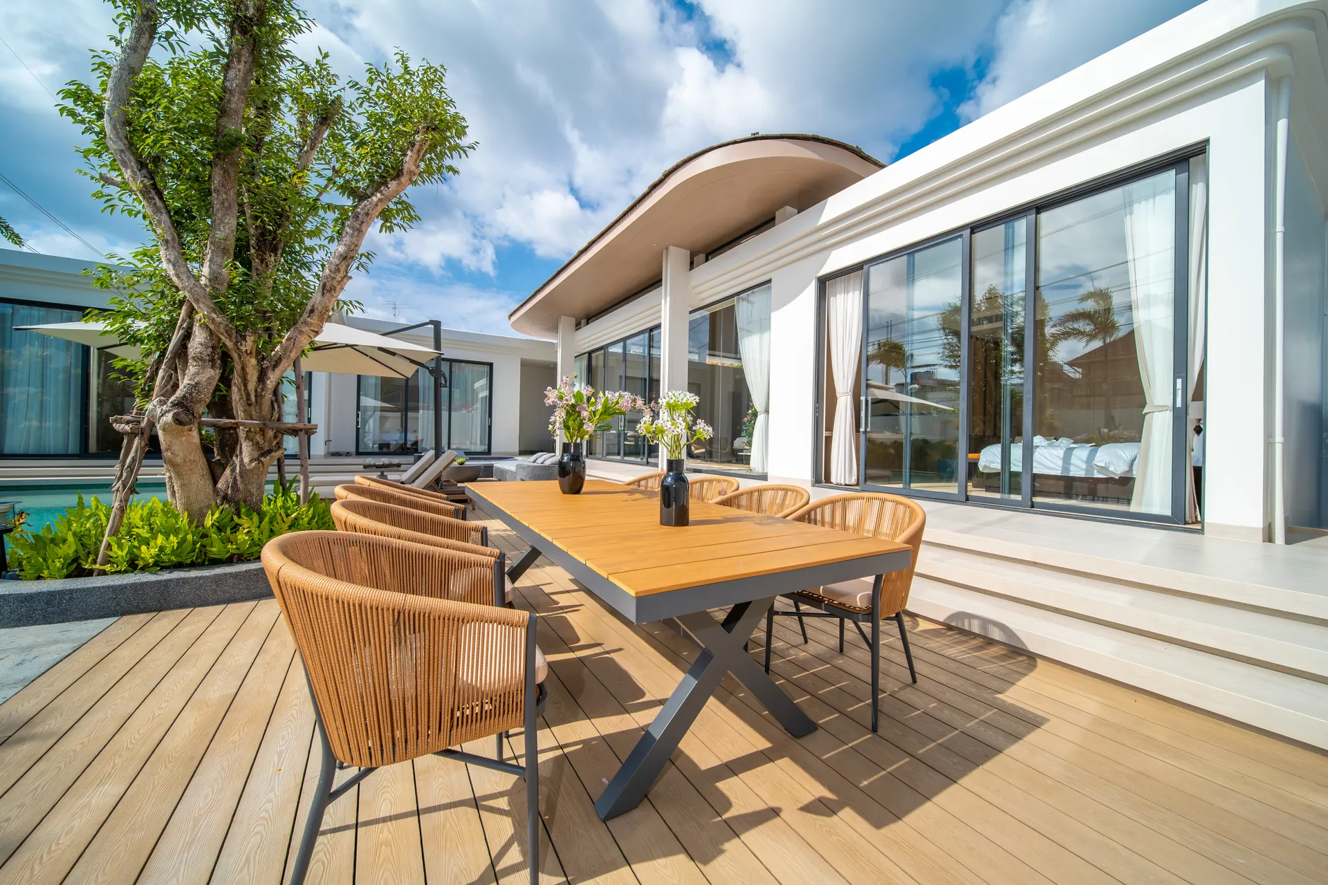 Eight-seat outdoor dining table on the deck beside a courtyard tree