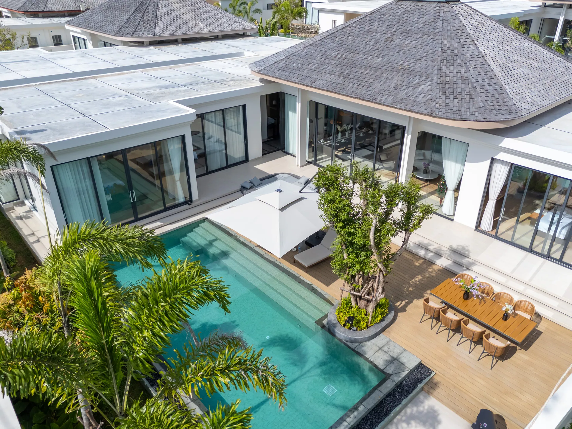 Elevated view of the pool, the parasol-shaded loungers and the outdoor dining table on the deck