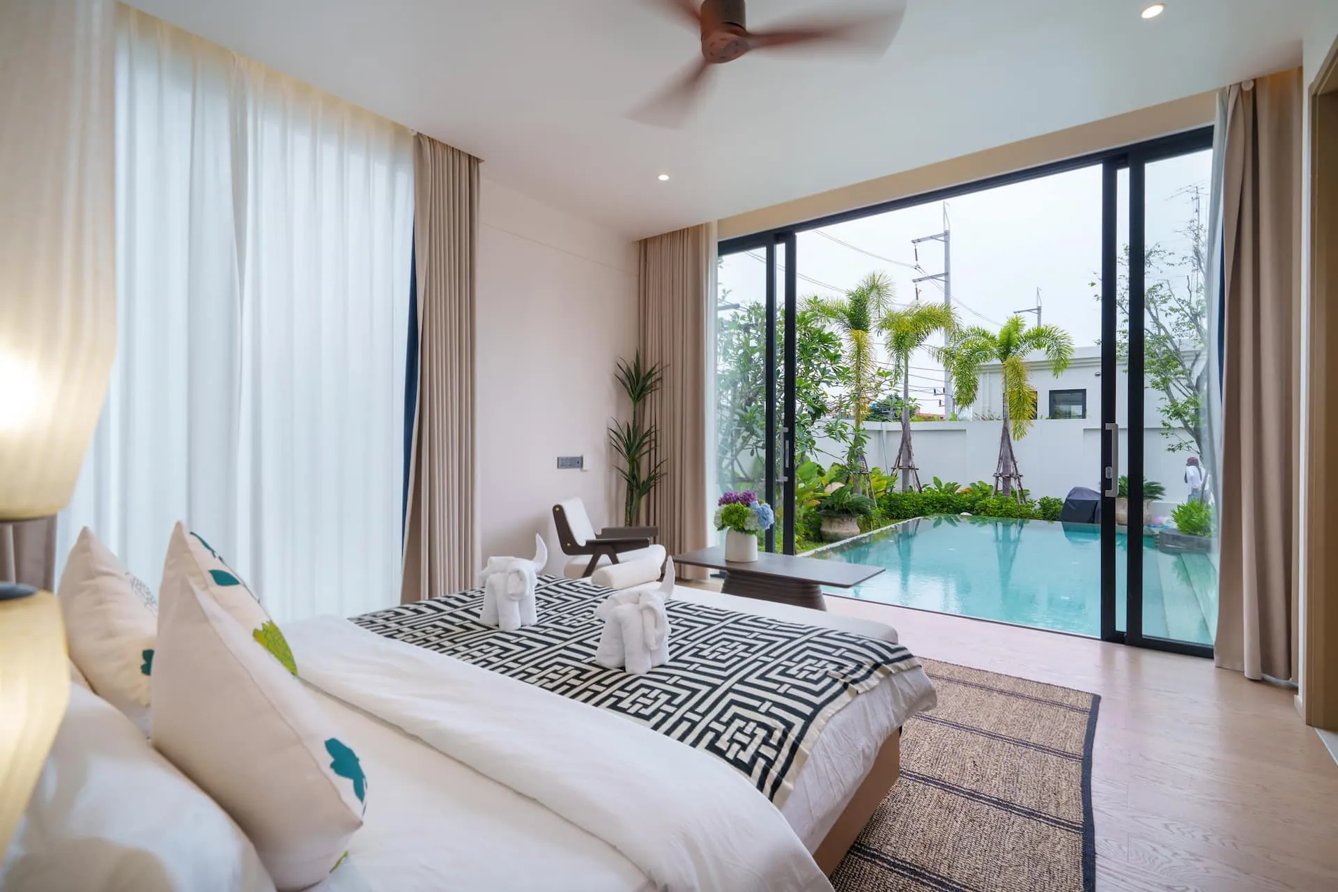 King bed facing full-height glass doors that open onto the pool