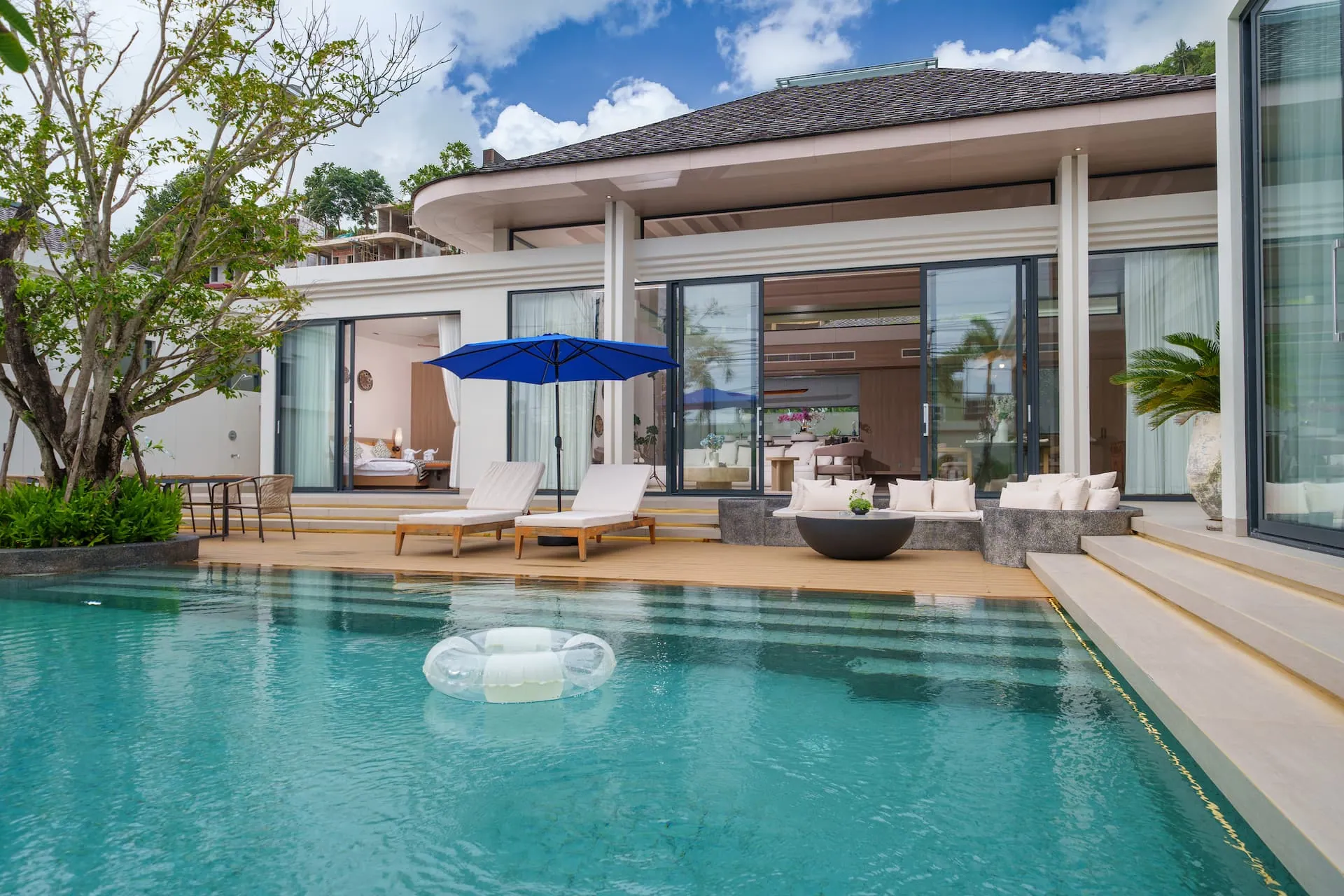 Private pool and timber sun deck in front of the villa under a blue sky