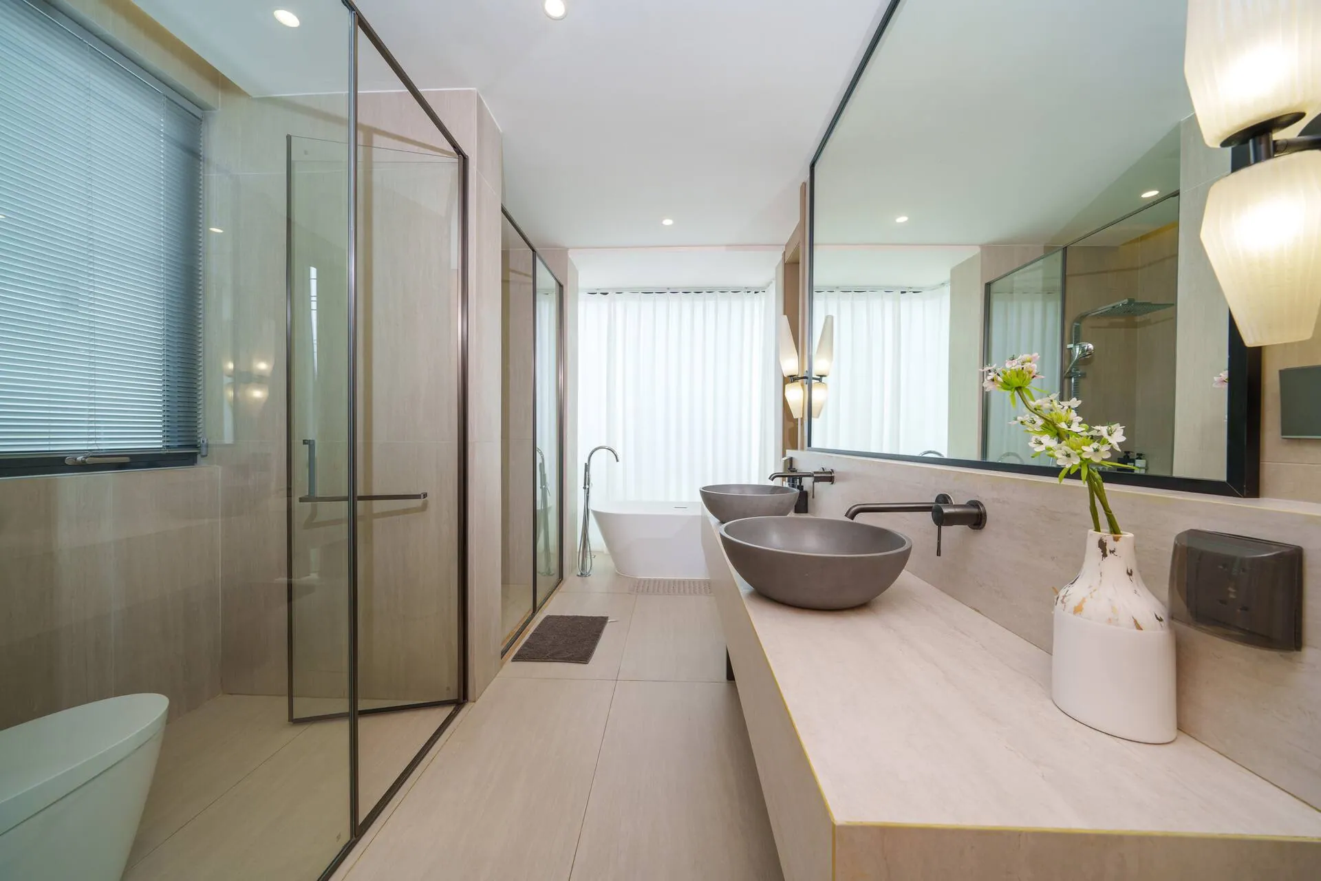 Long vanity with a vessel basin, a glass-walled shower and a freestanding bath beyond