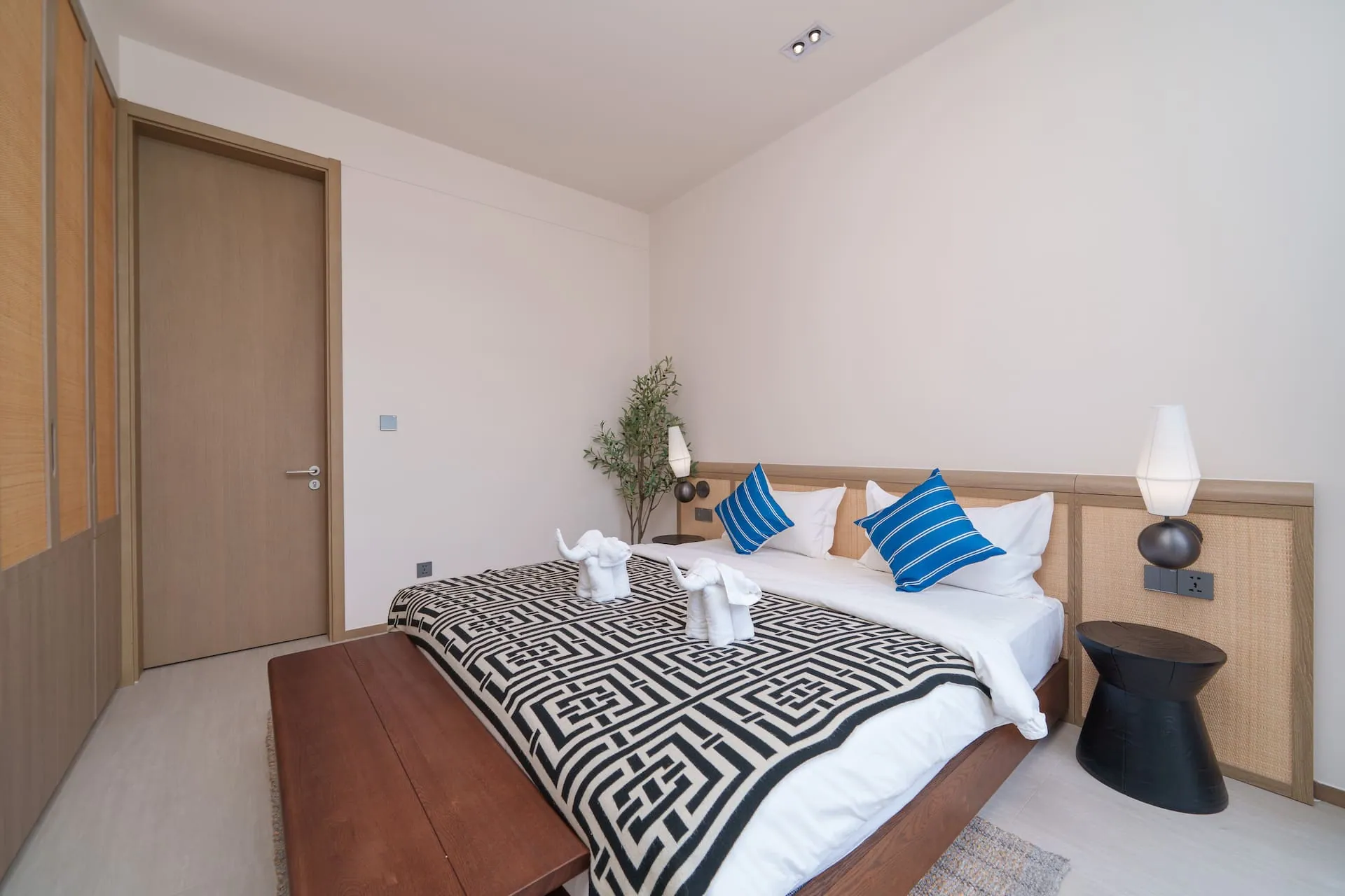 Bedroom with a king bed, blue-striped cushions and timber wardrobe doors