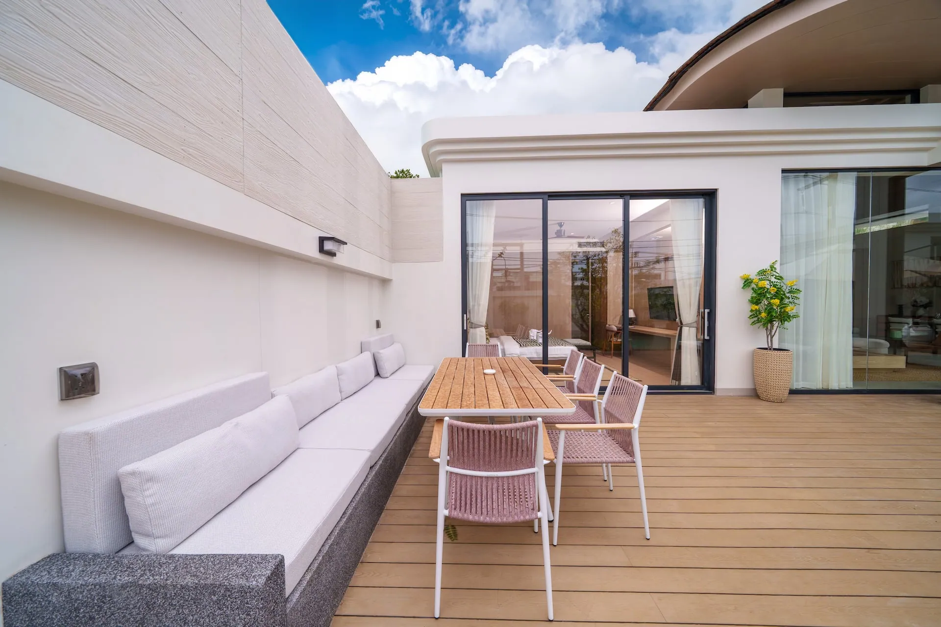Side terrace with a built-in sofa and an outdoor dining table beside the bedroom wing