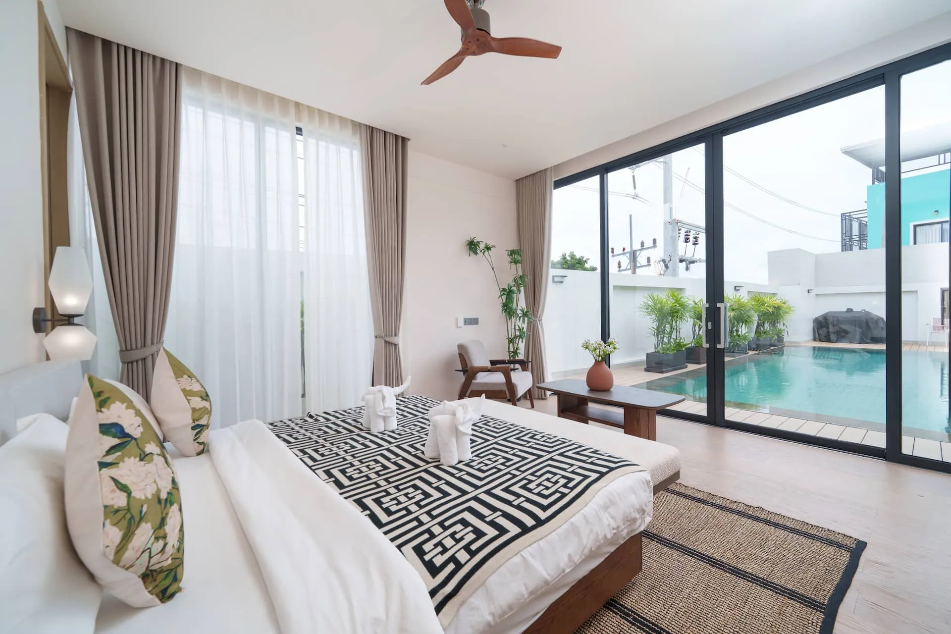 Bedroom with a king bed and full-height glass doors looking onto the pool