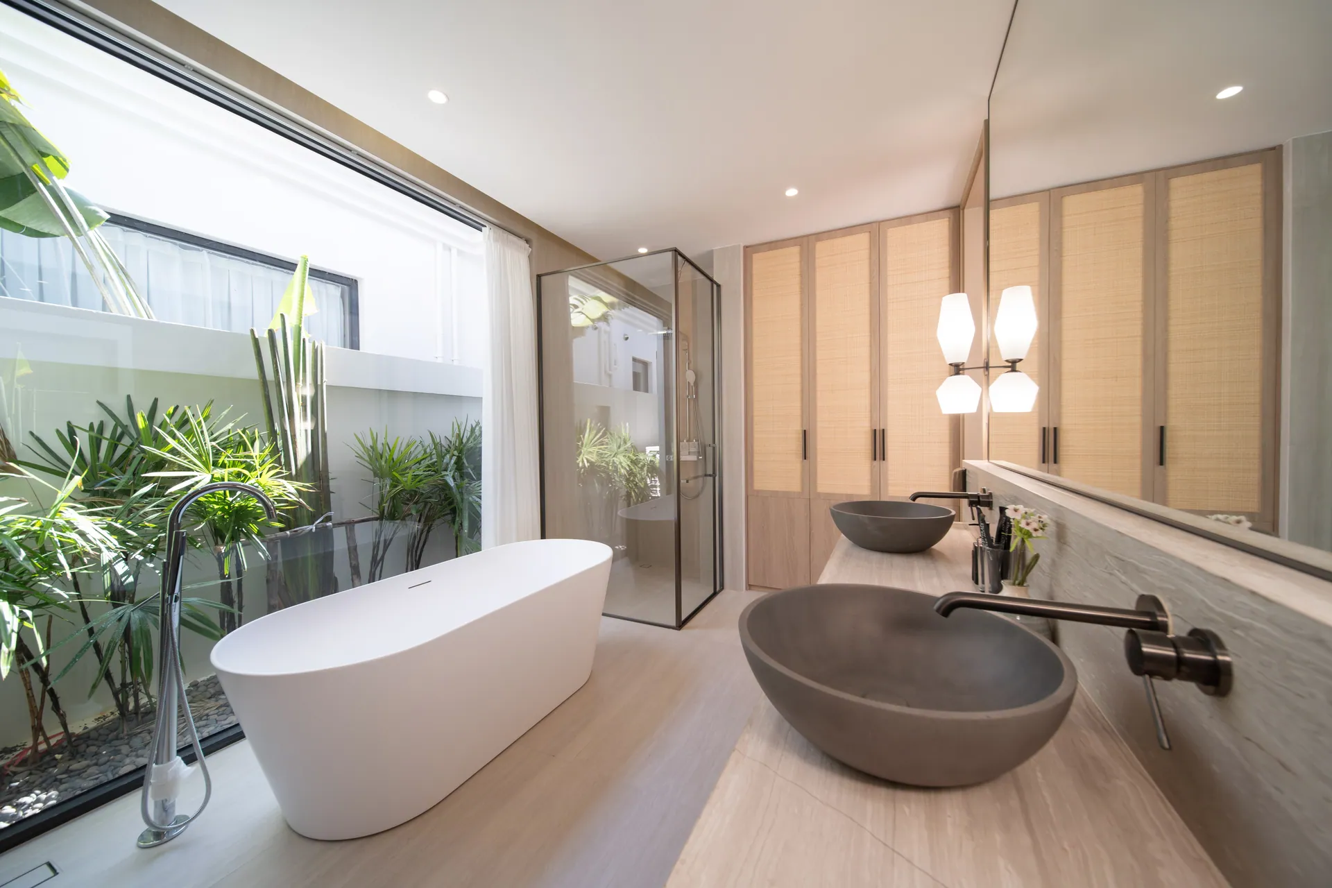Master bathroom with a freestanding bath and a stone vessel basin, beside a window onto planting