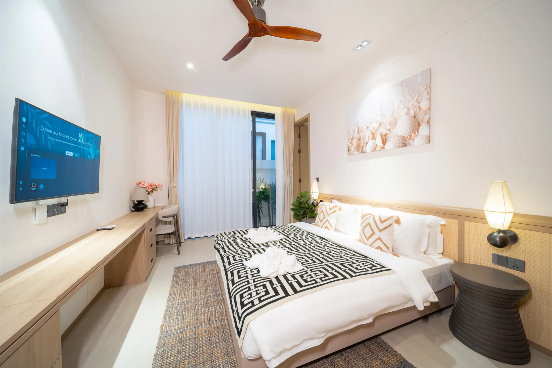 Bedroom with a king bed, a wall-mounted TV, a long desk and a ceiling fan