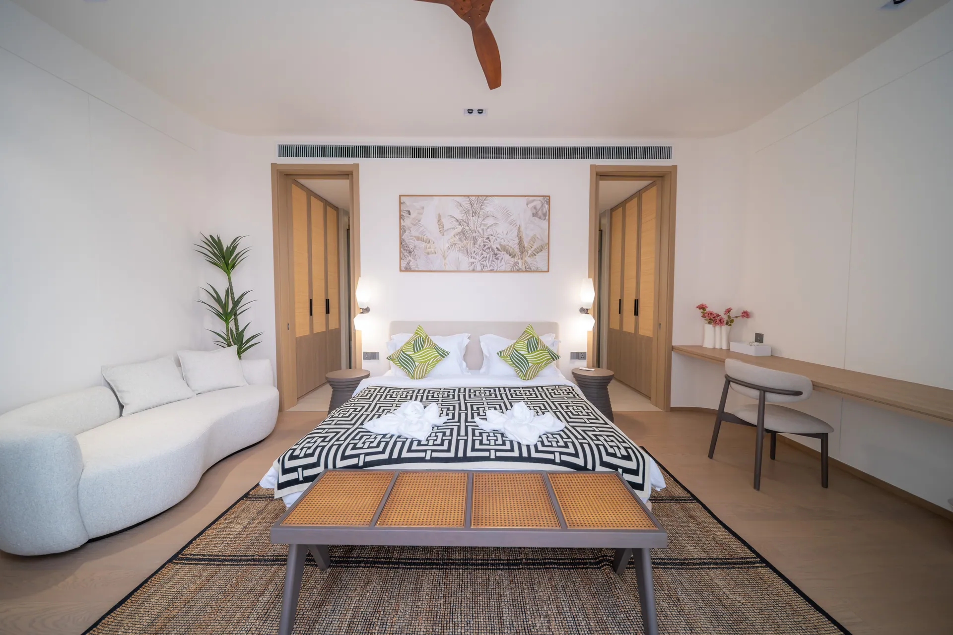 Bedroom with a king bed, botanical artwork and a curved white sofa