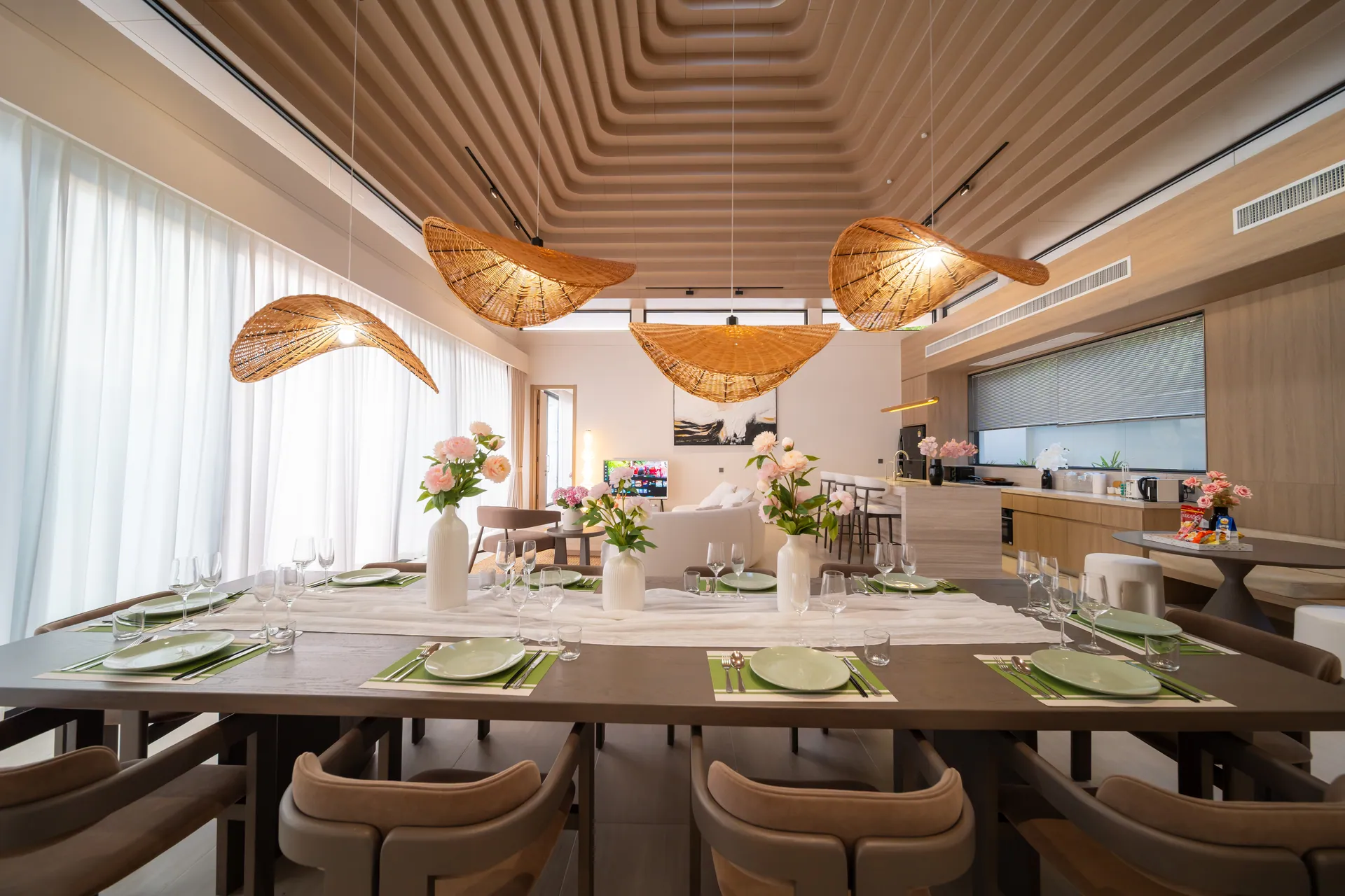 Dining table laid for a meal beneath woven leaf-shaped pendant lights