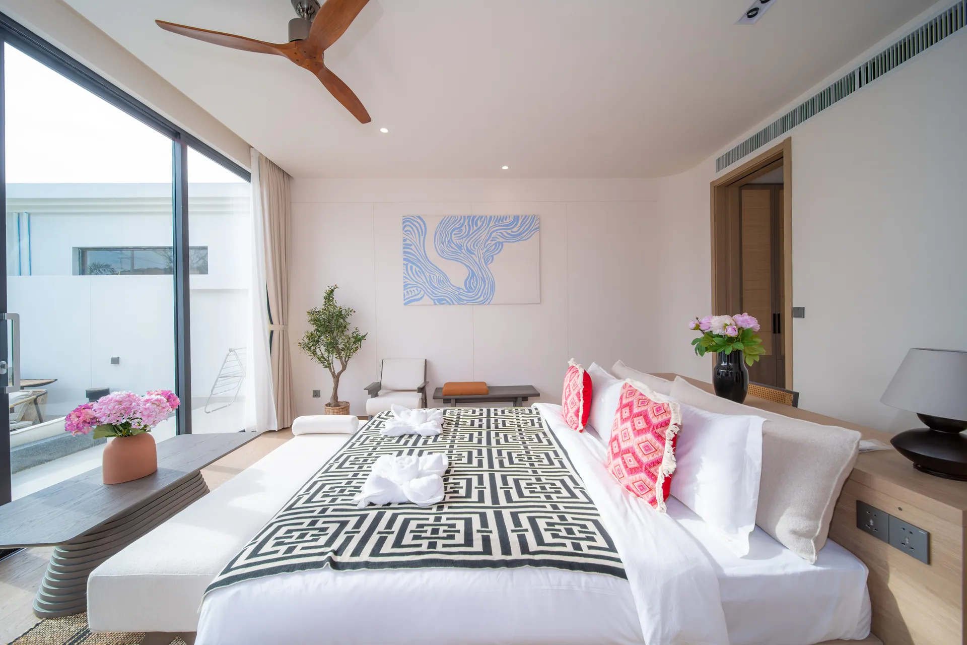 Bedroom with a king bed, a black-and-white throw, blue abstract artwork and floor-to-ceiling glass doors