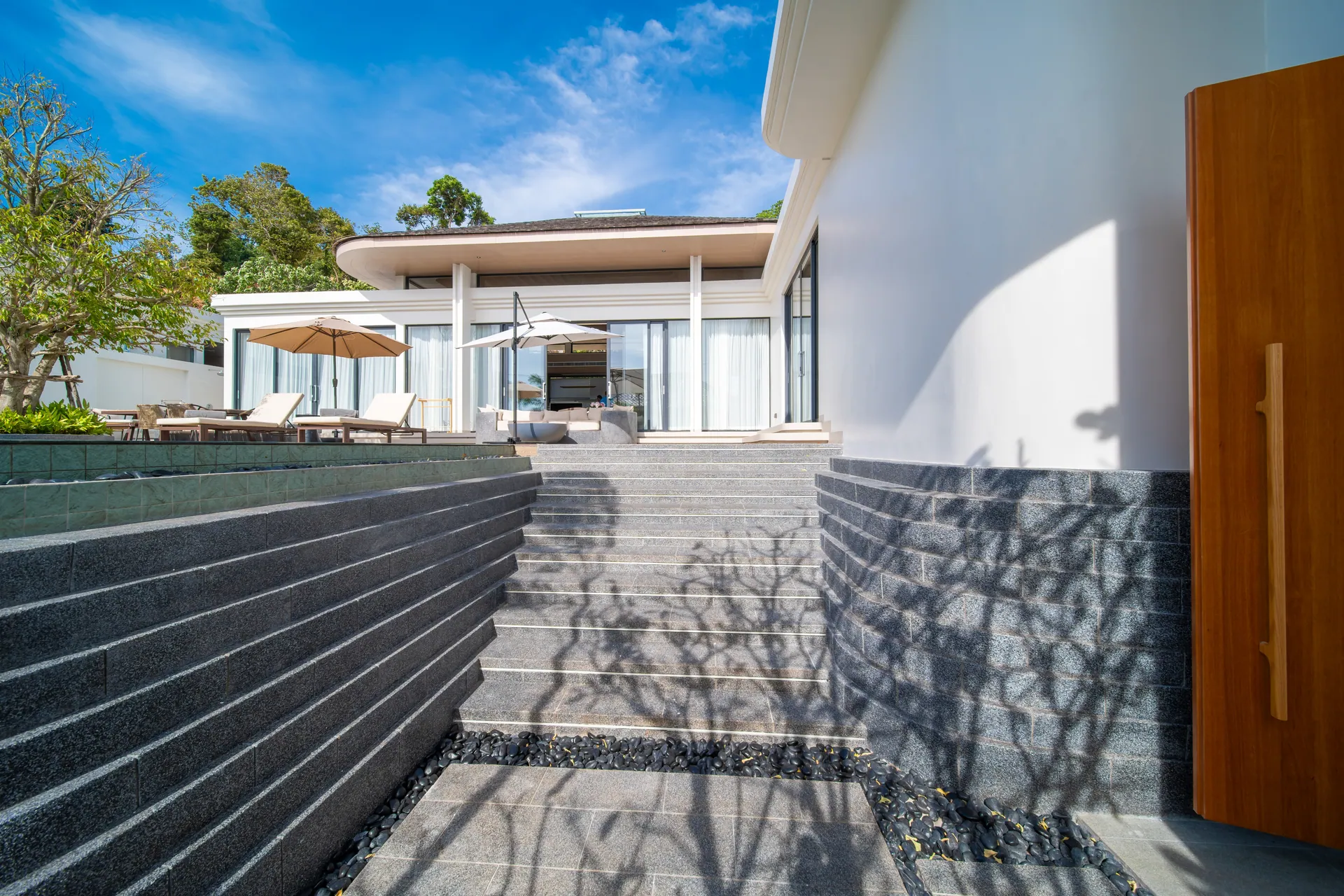 Stone steps from the entrance door rising to the pool terrace and the living pavilion