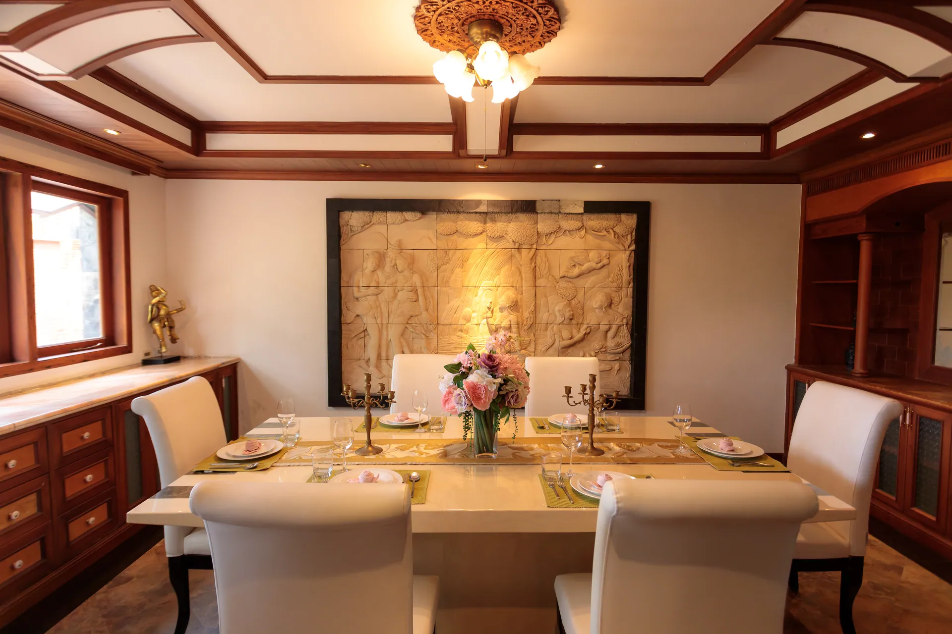 Dining table laid for dinner beneath a large carved stone relief