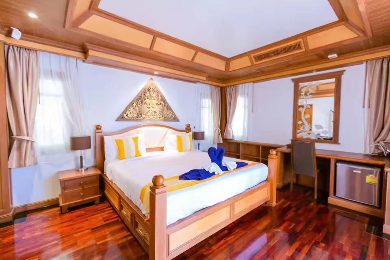 Bedroom 4 with a king bed under a gilded gable carving, desk and small fridge