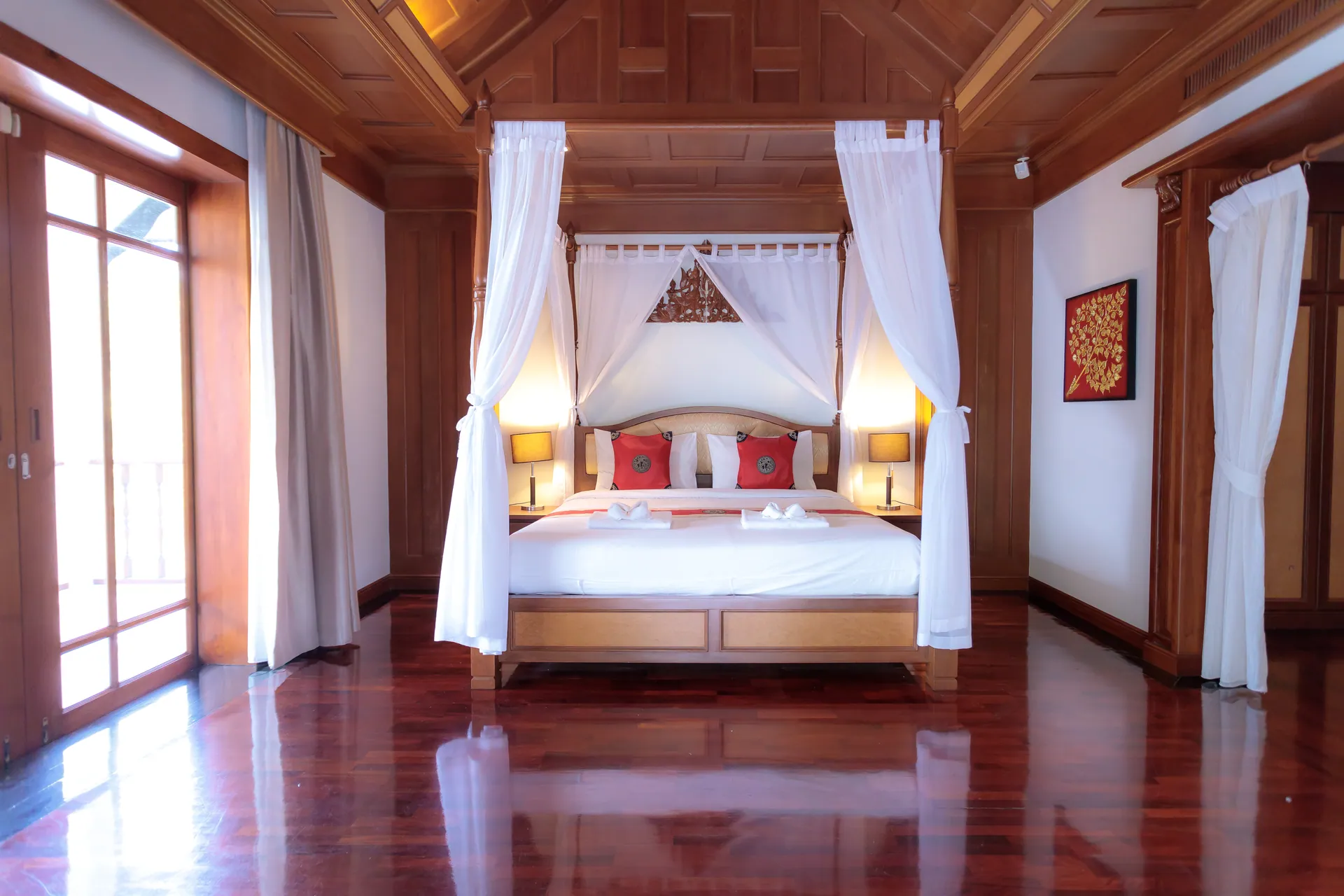 Bedroom 1 with a four-poster king bed, white drapes and glass doors on both sides