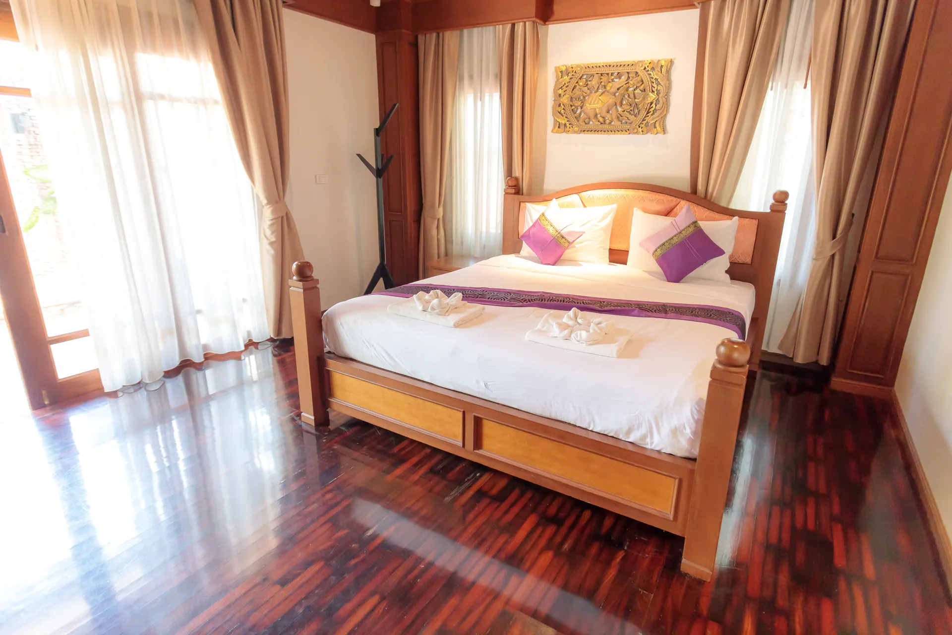 Bedroom 3 with a king bed below a gilded carved panel and full-length curtains