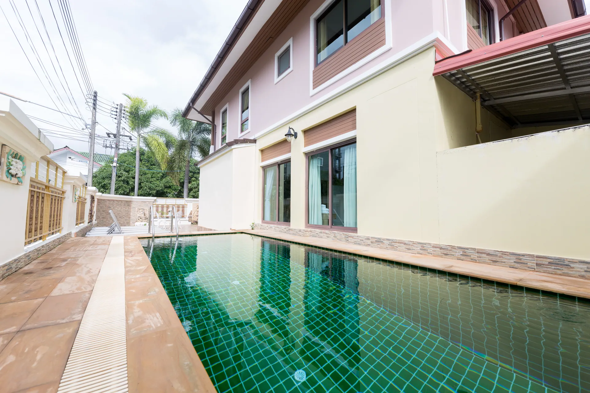 Private pool running alongside the two-storey villa, with a tiled deck on one side