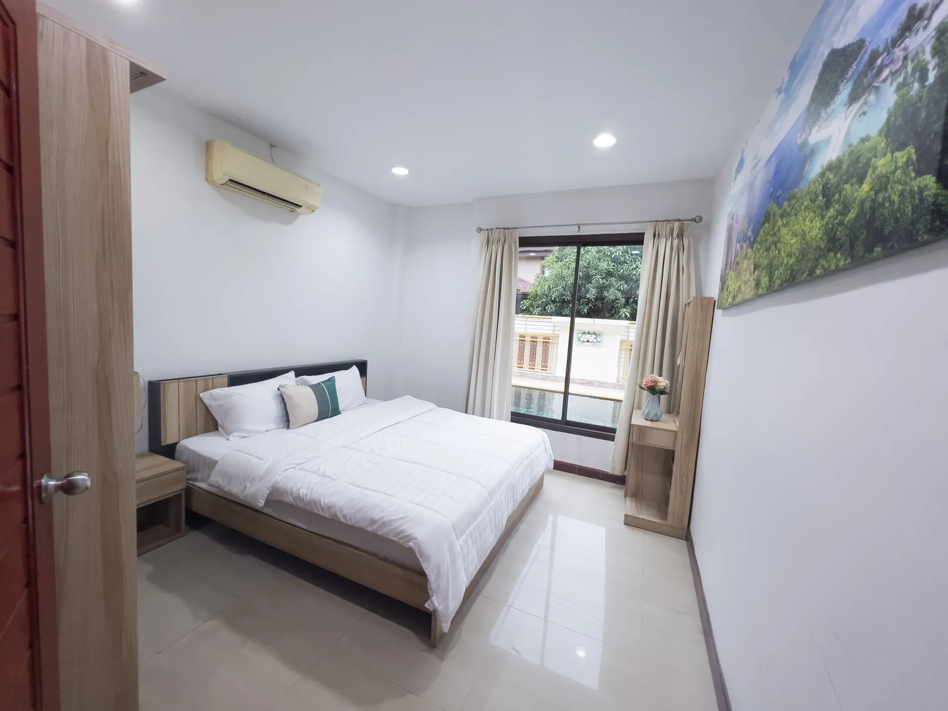 Bedroom with a king bed, a large landscape canvas and a window at the far end