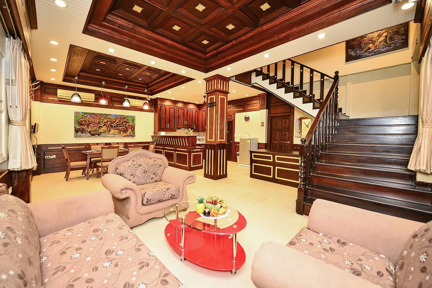 Ground-floor living room with upholstered sofas, a teak staircase and the dining area beyond
