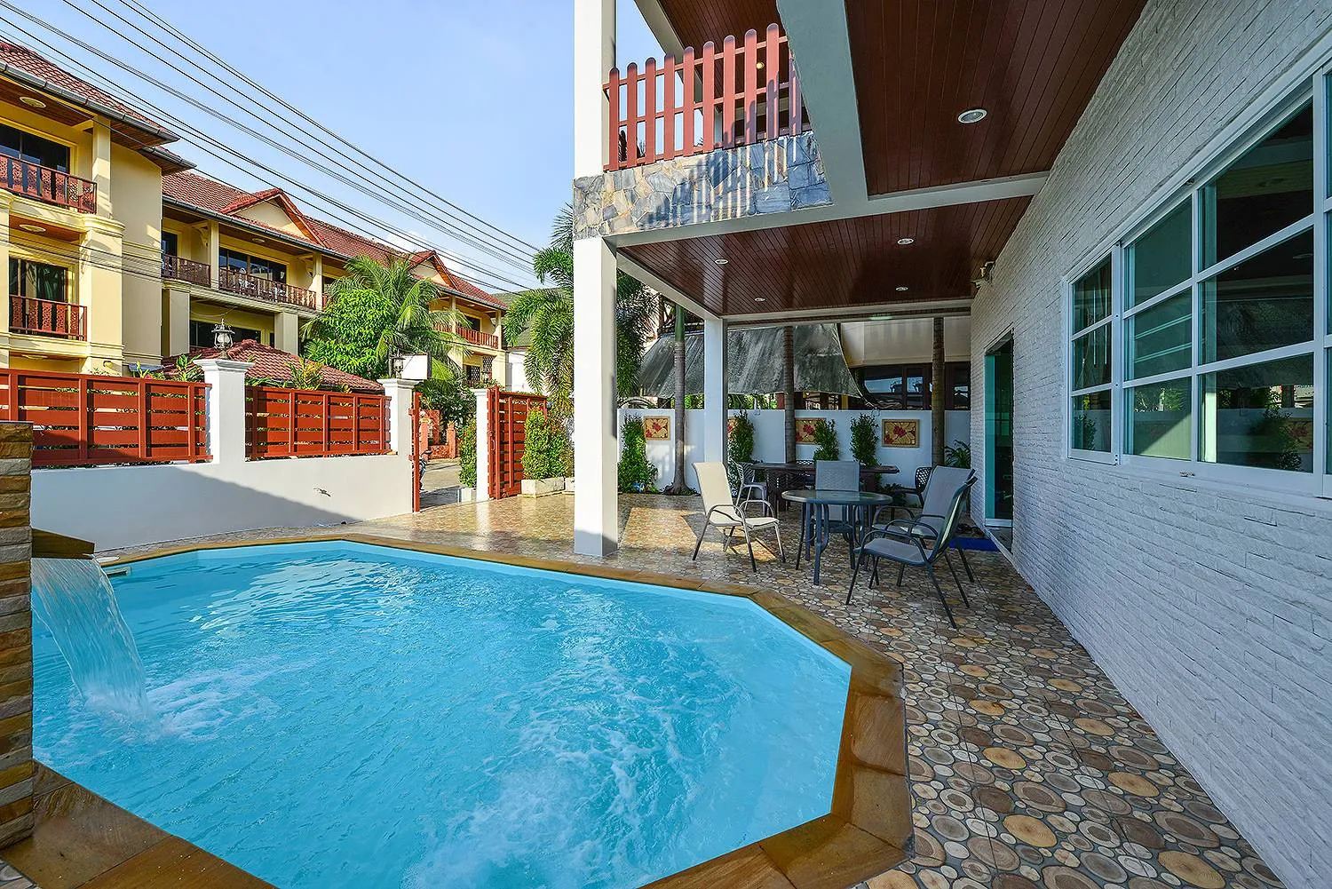 Private pool in daylight with the tiled pool deck and the villa's side wall