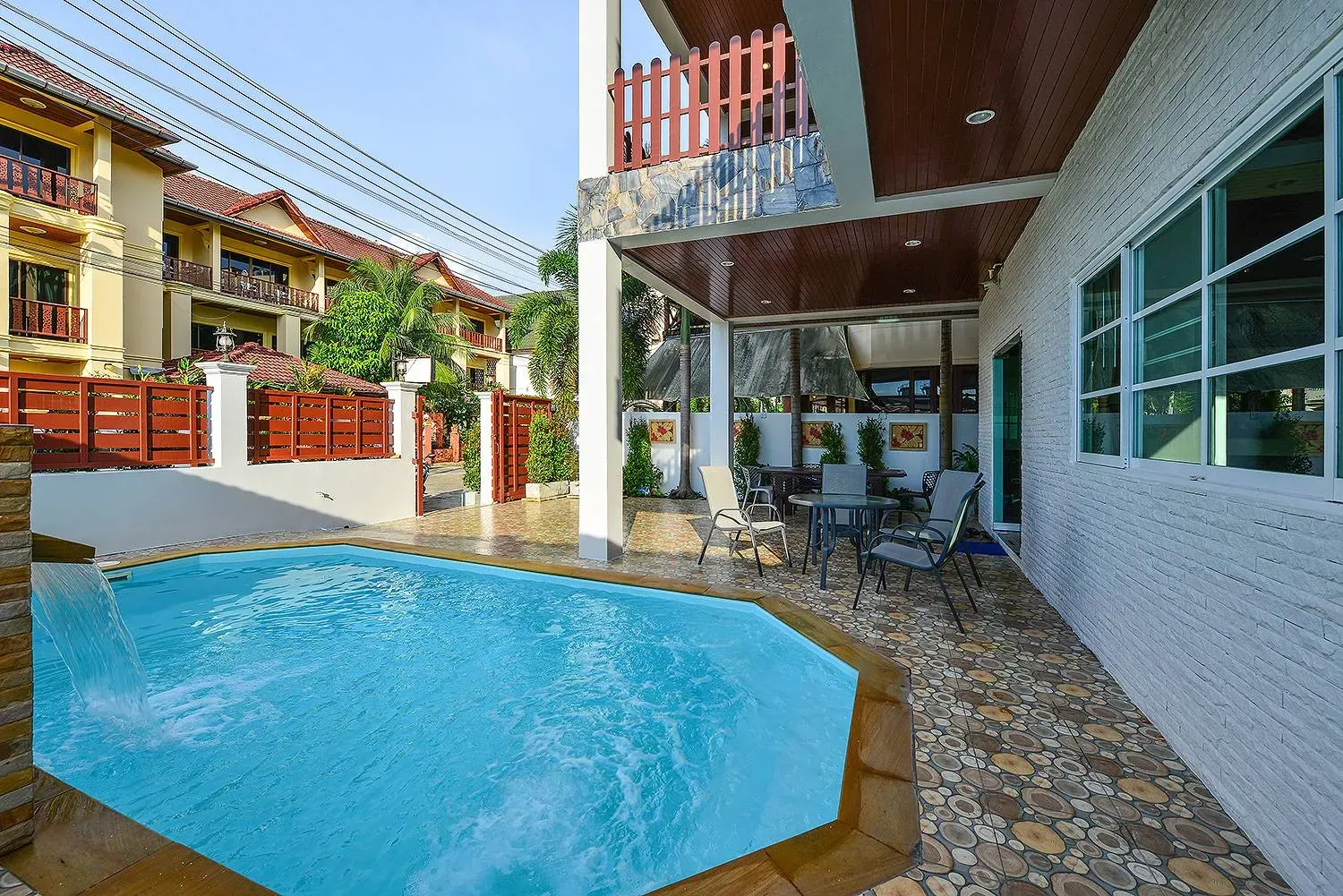 Private pool in daylight with the tiled pool deck and the villa's side wall