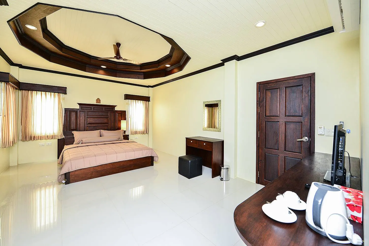 Bedroom with a king bed under an octagonal tray ceiling, a dressing table and a kettle
