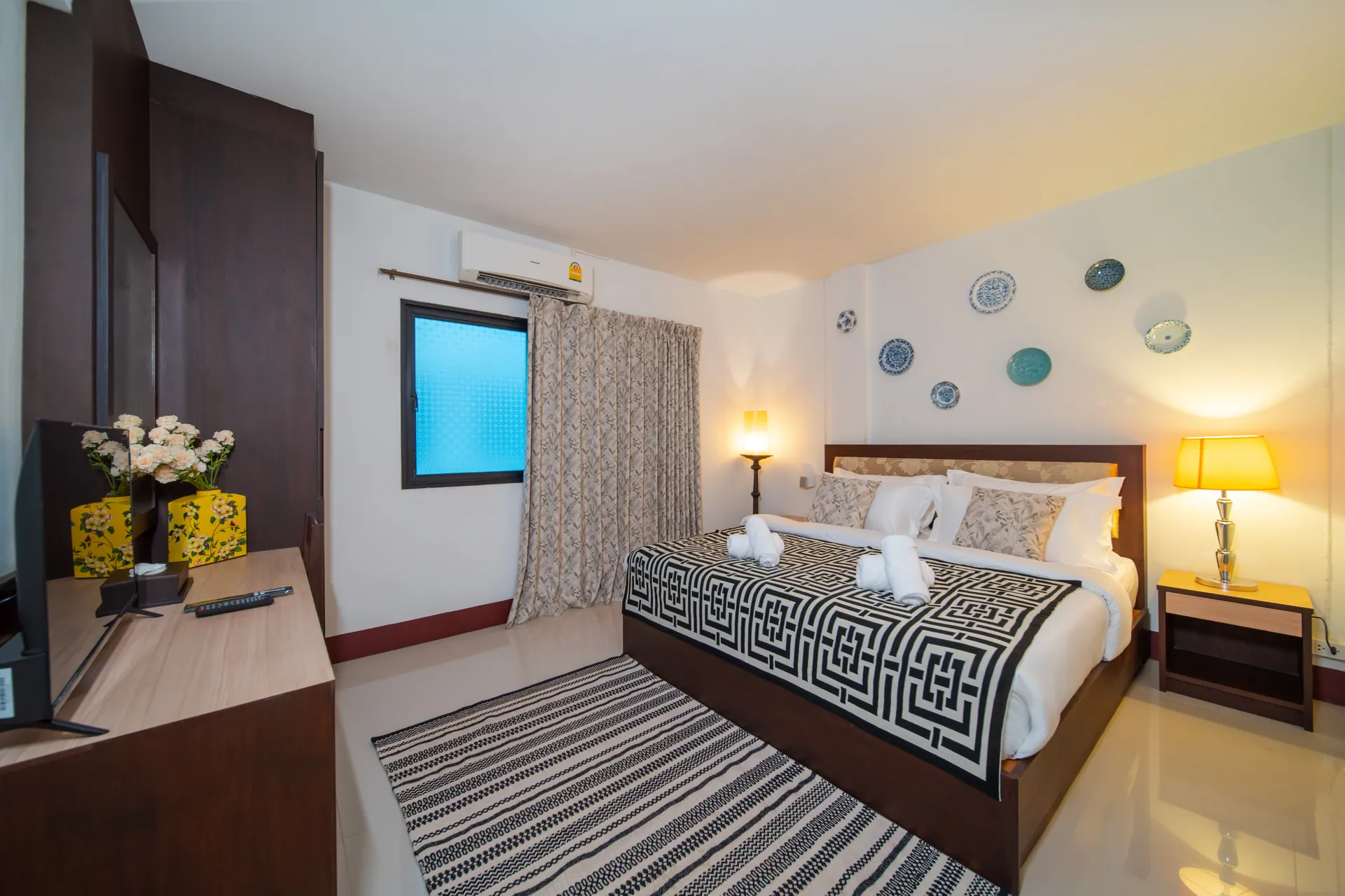 King Room with a patterned bedspread, bedside lamps and blue-and-white plates on the wall