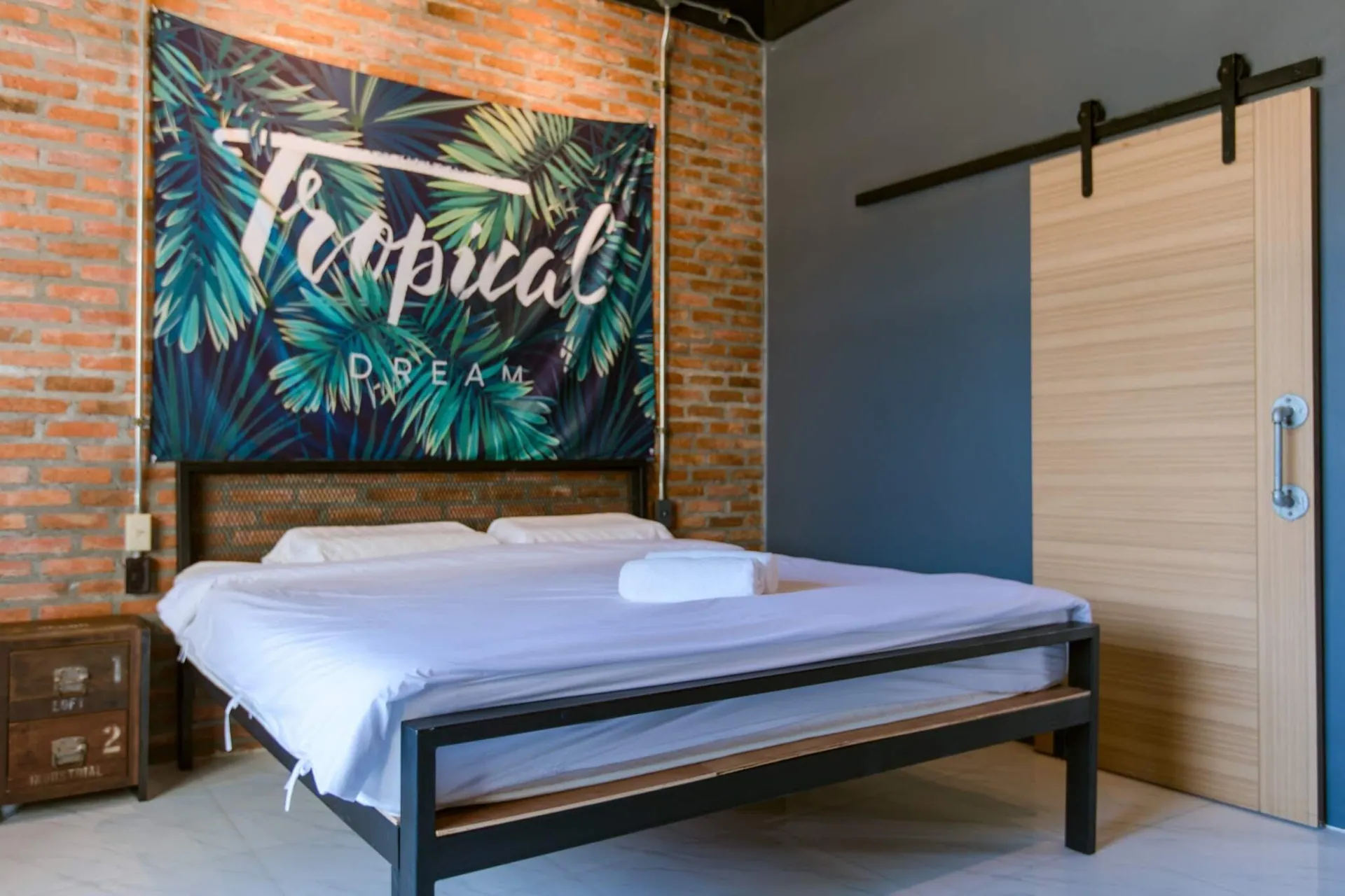 King bedroom with a tropical print wall hanging and a sliding barn door