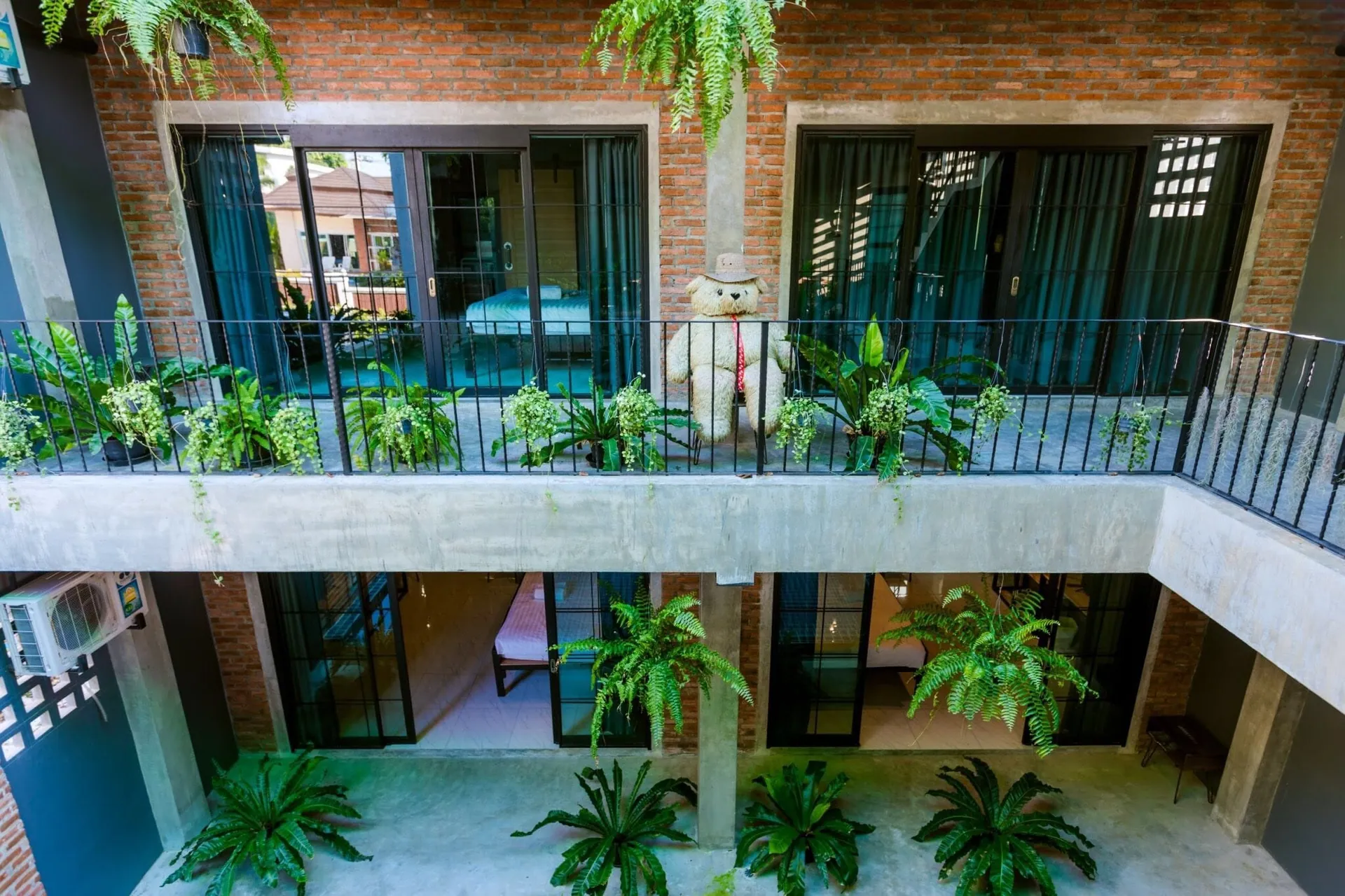 Upper-floor balconies lined with potted plants above the ground-floor rooms