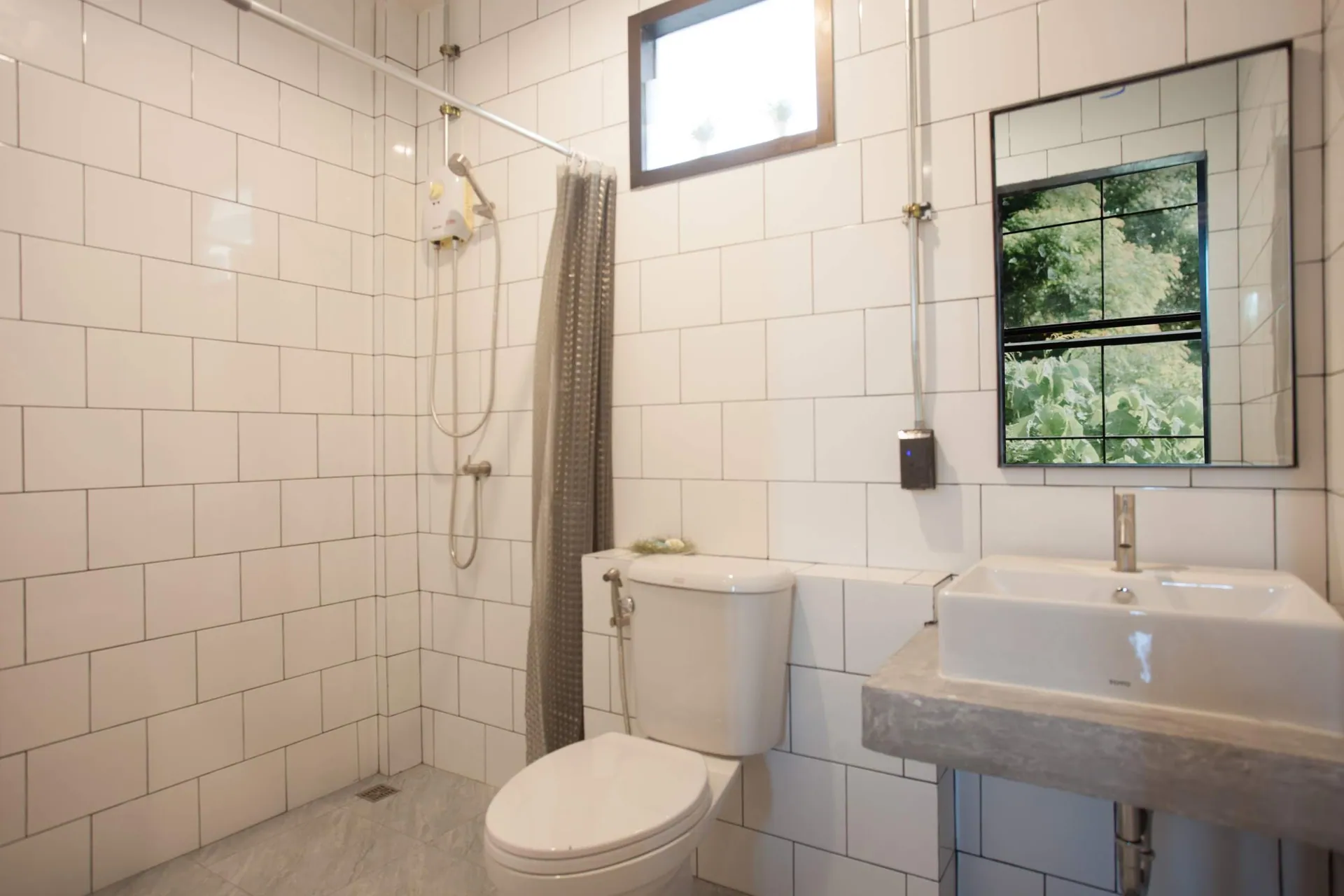 White-tiled bathroom with a shower, basin and window