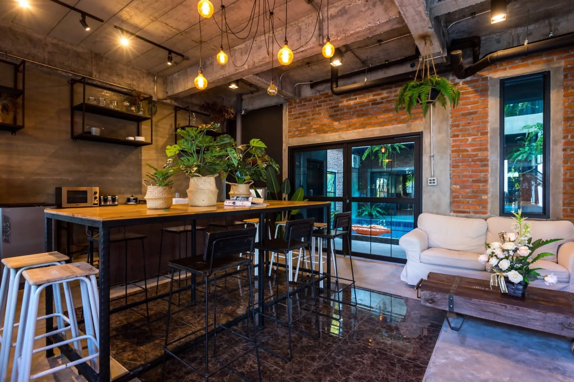 Open-plan living and dining room with pendant lights, a long table and a white sofa