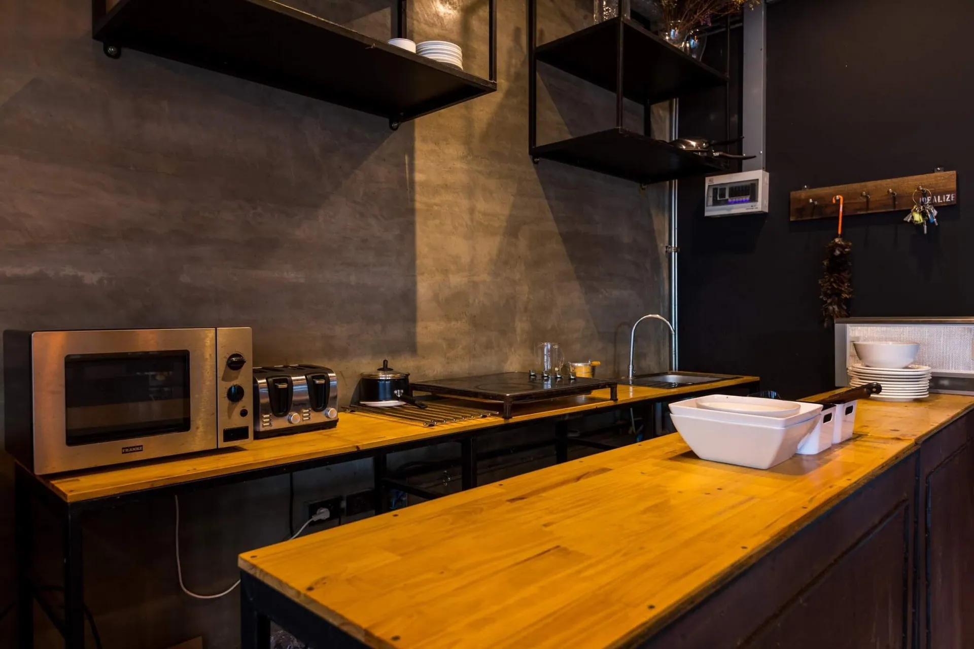 Kitchen with a timber counter, induction hob, microwave and open steel shelving