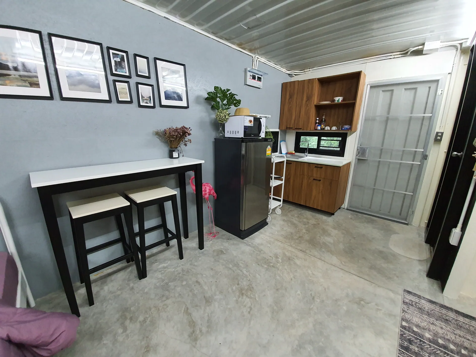 Breakfast bar with two stools beside a kitchenette with a fridge, microwave and wood-finish cabinets