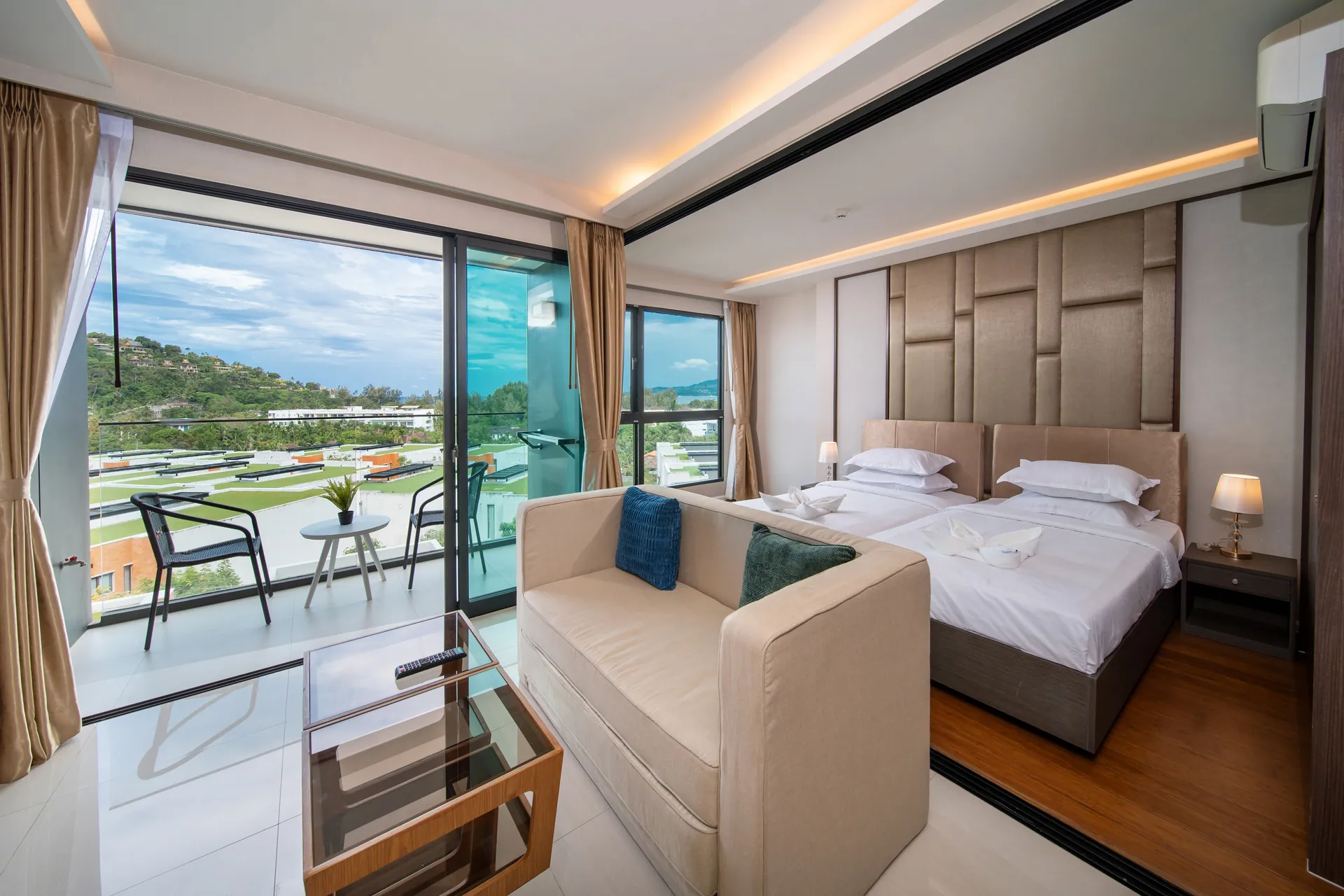 Twin beds and a sofa, with glass doors to a balcony