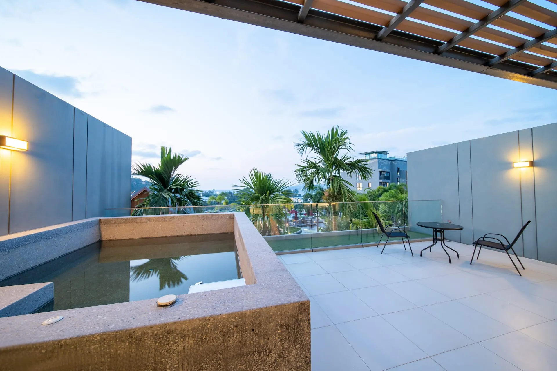 Large terrace with a built-in plunge tub, a table and chairs, at dusk
