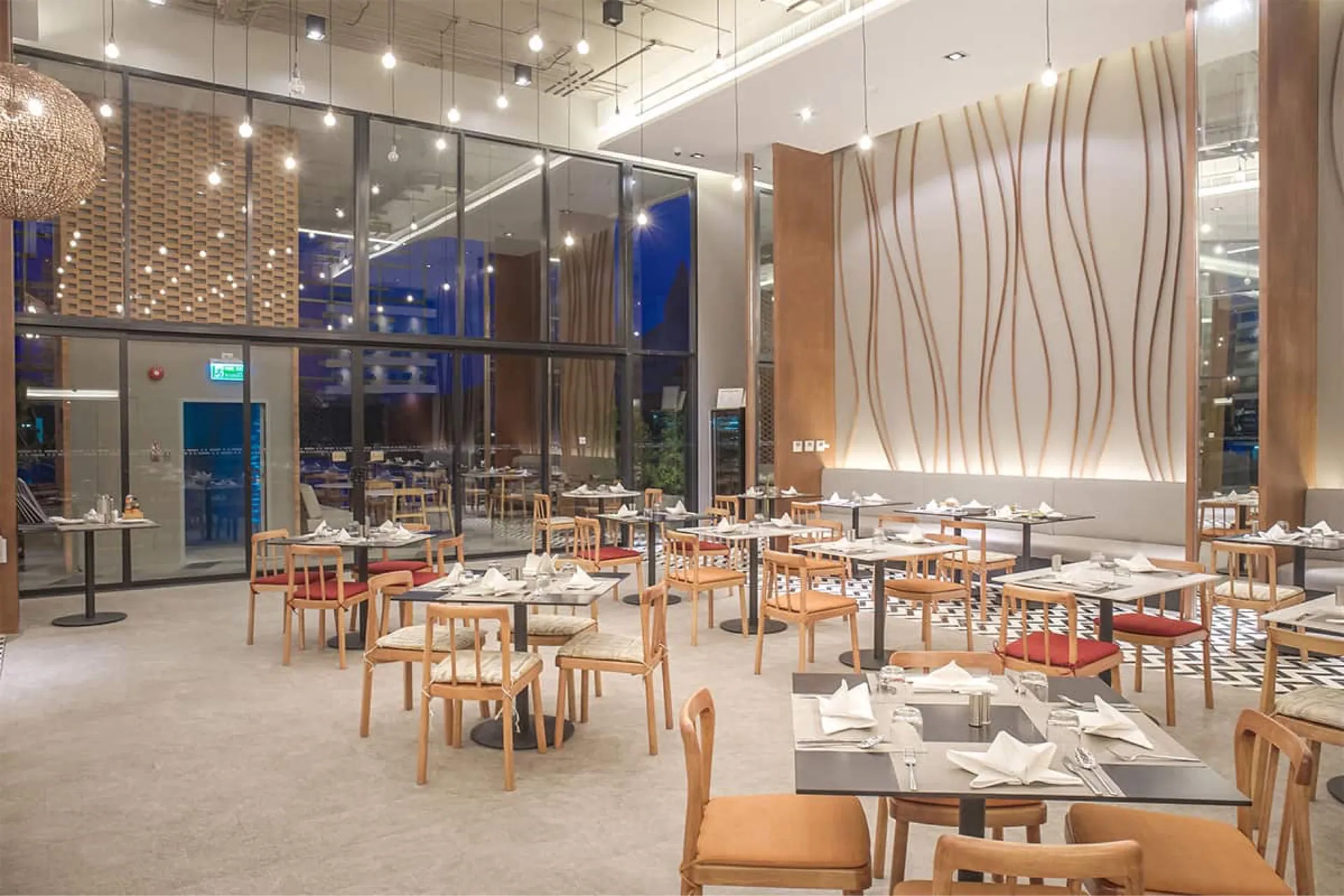 Restaurant with wooden chairs, laid tables and full-height windows